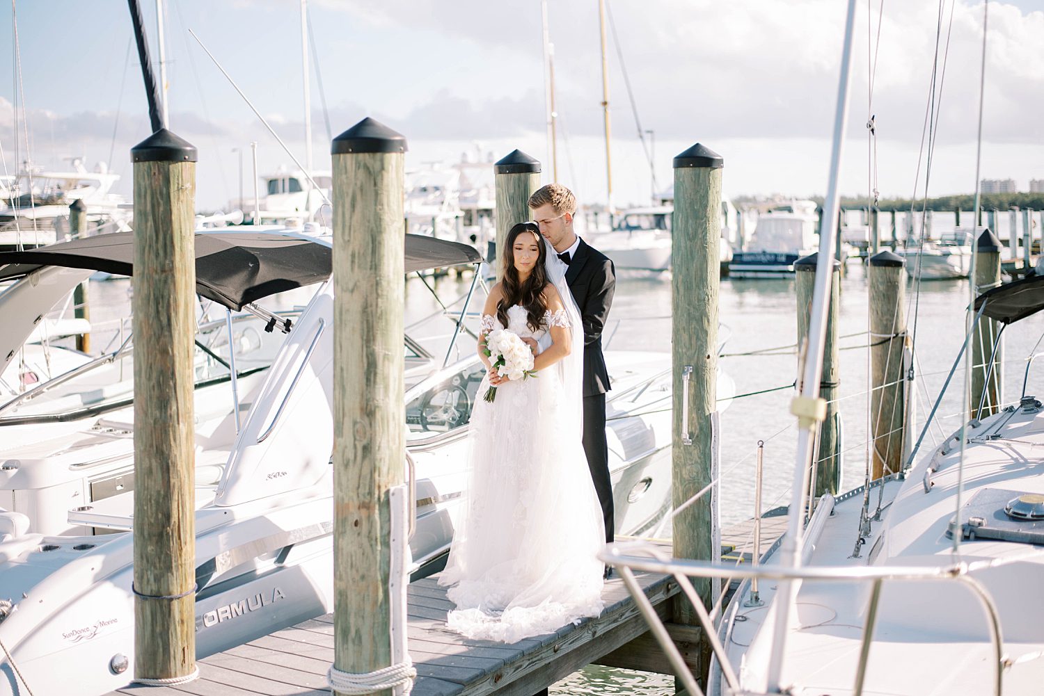 bride and groom hug on dock at Sarasota Yacht Club