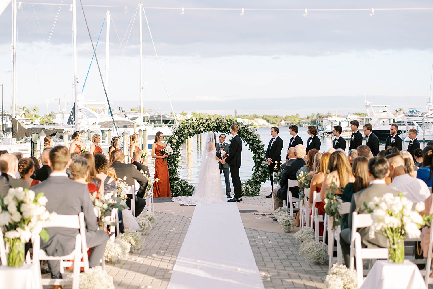 bride and groom stand under arbor for ceremony at Sarasota Yacht Club