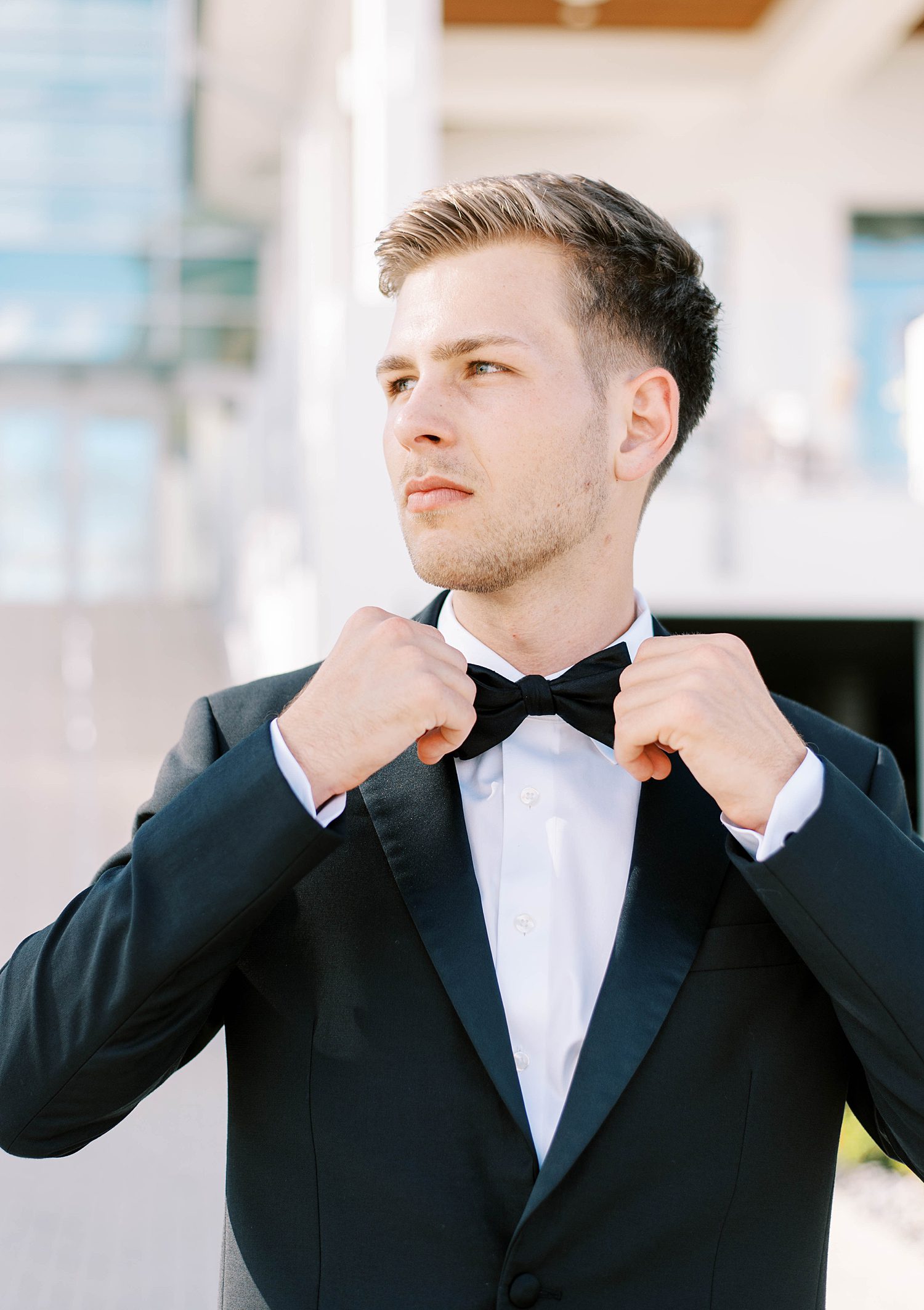 groom adjusts bowtie standing outside Sarasota Yacht Club