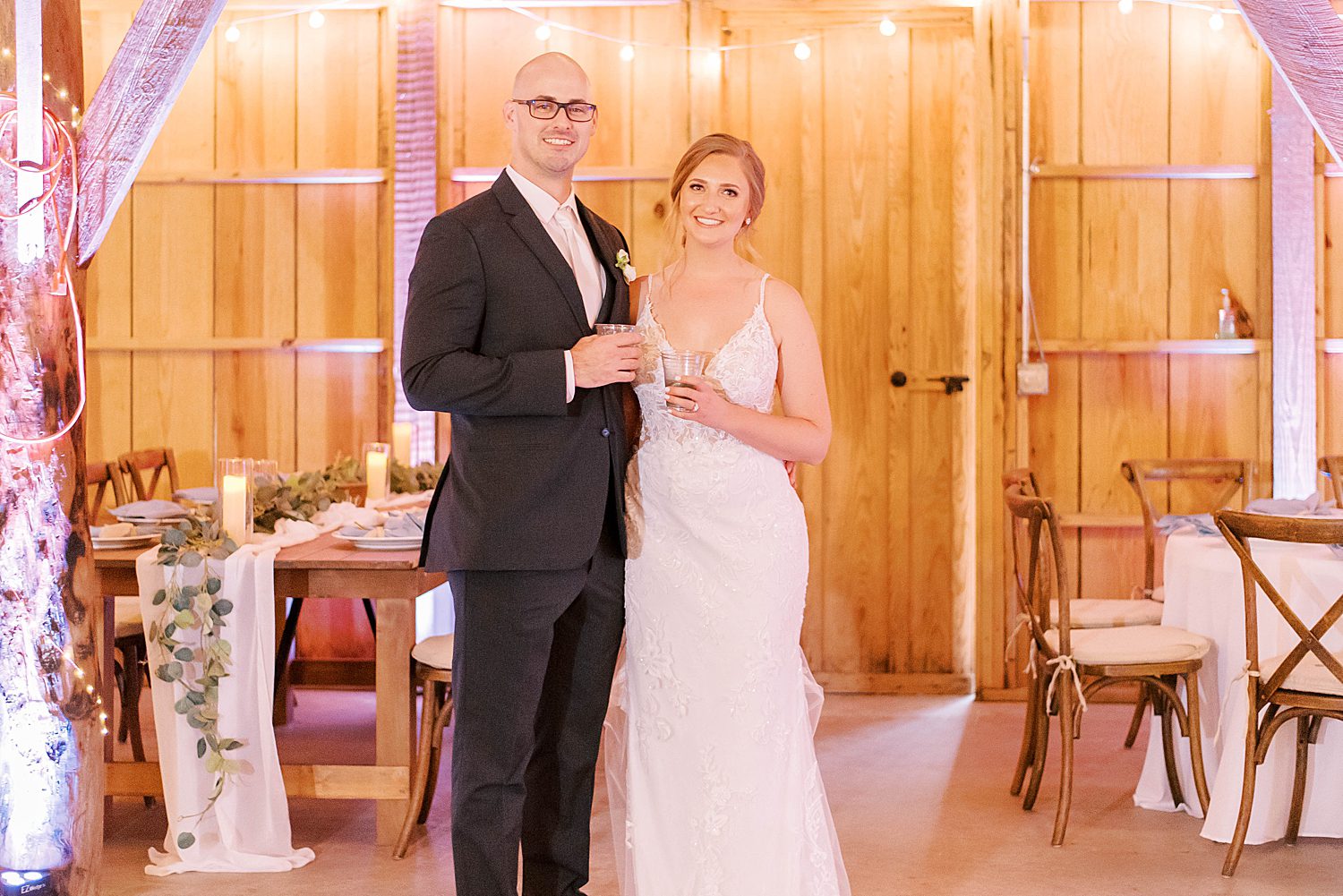 bride and room pose with glasses inside The Barn at Lone Oak Acres