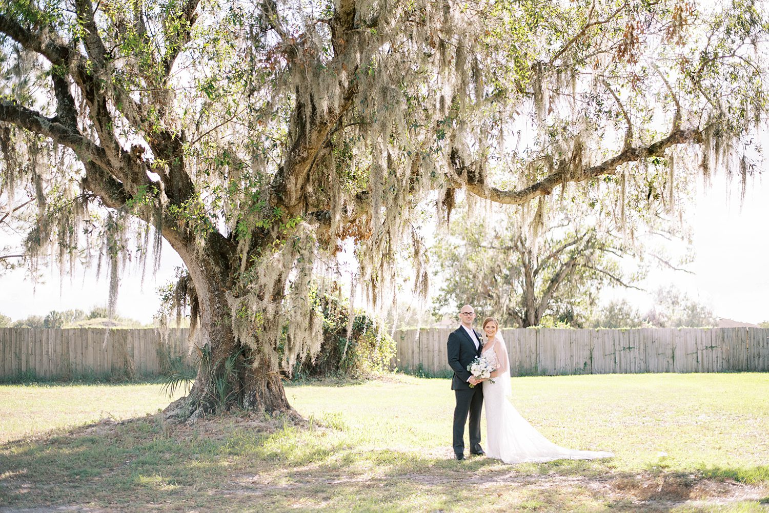 bride and groom hug under oak tree at The Barn at Lone Oak Acres