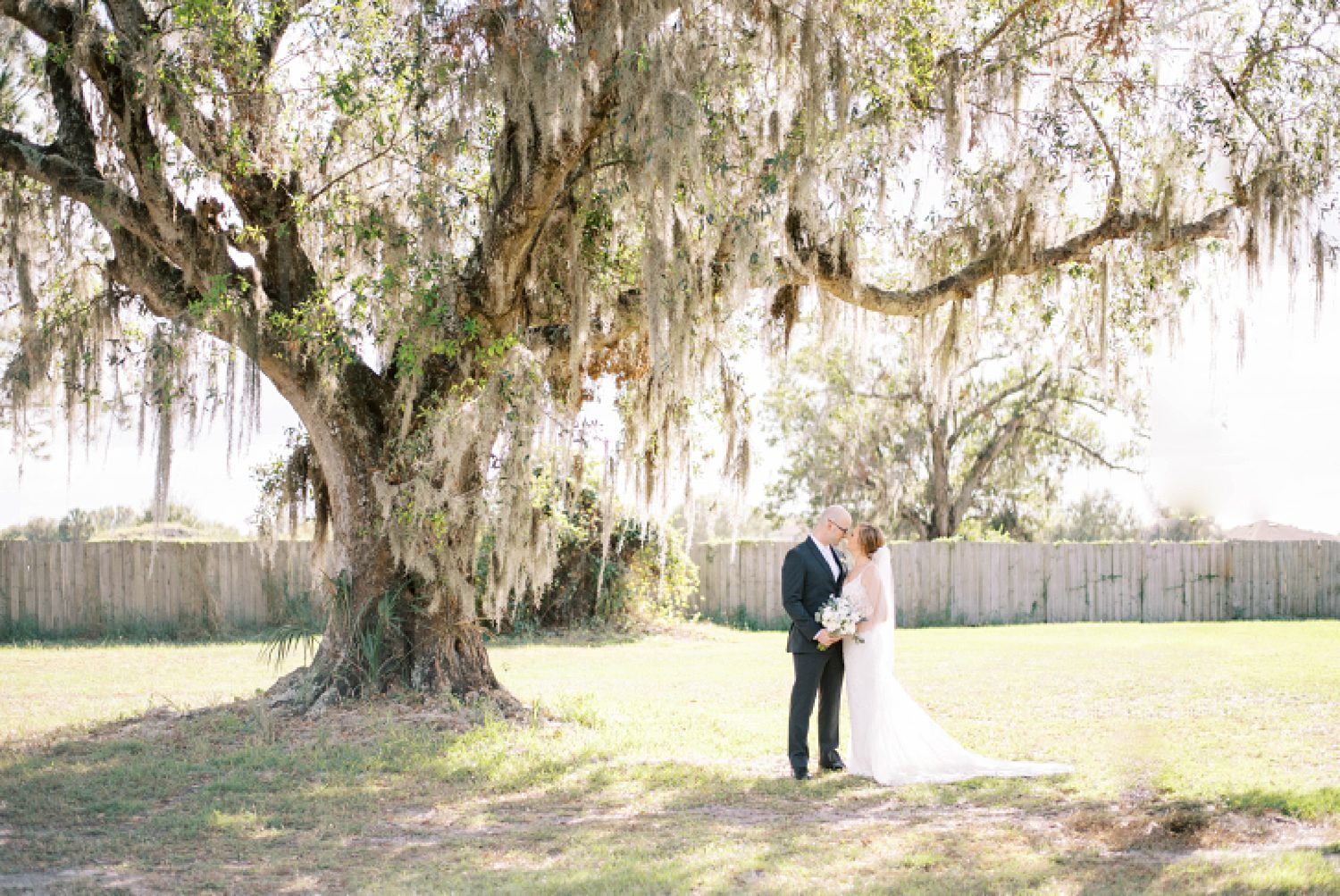 newlyweds hug under oak tree during portraits in Tampa FL