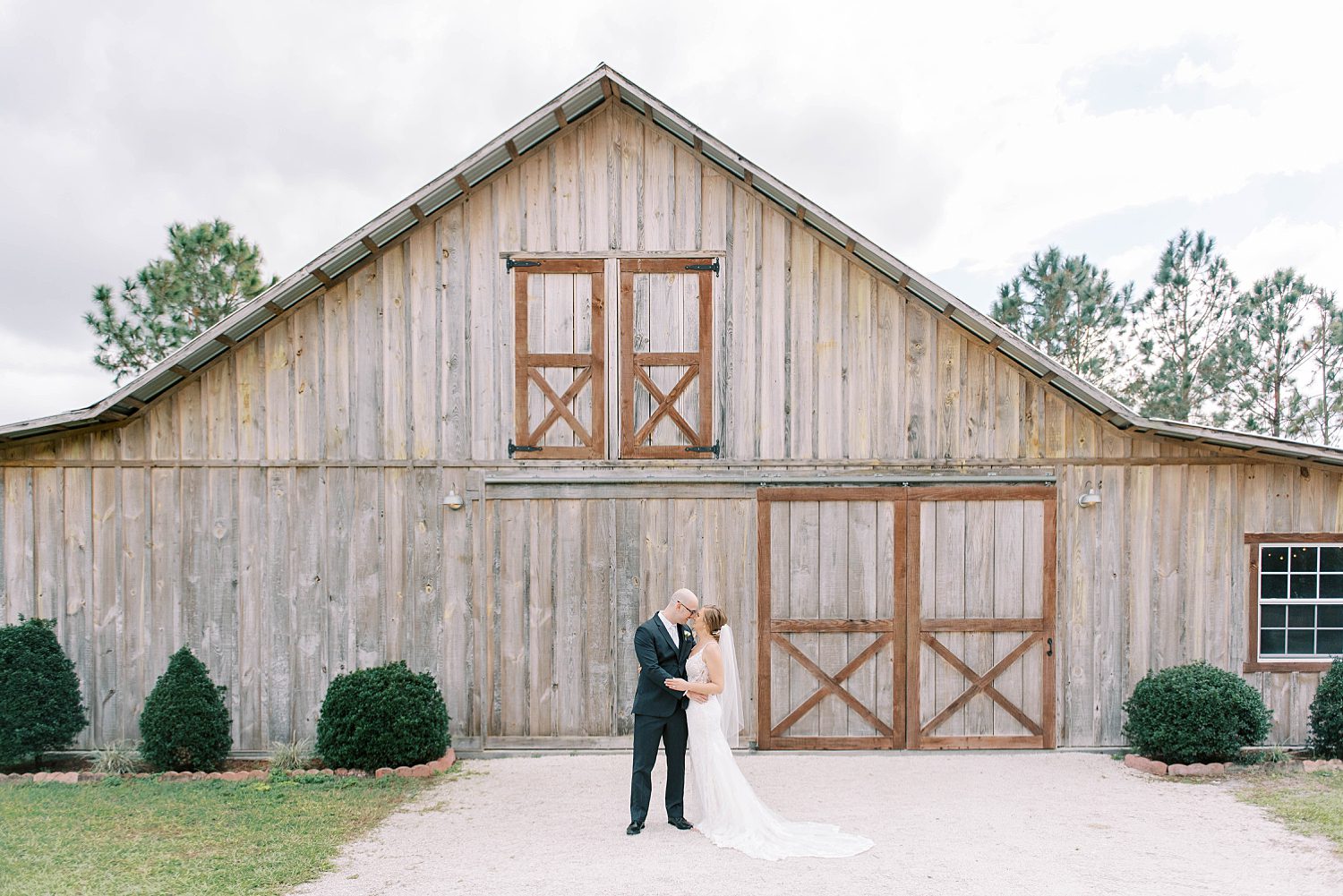 bride and groom stand outside barn at The Barn at Lone Oak Acres