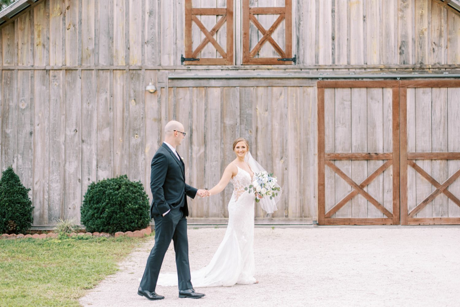 bride leans groom outside barn at The Barn at Lone Oak Acres