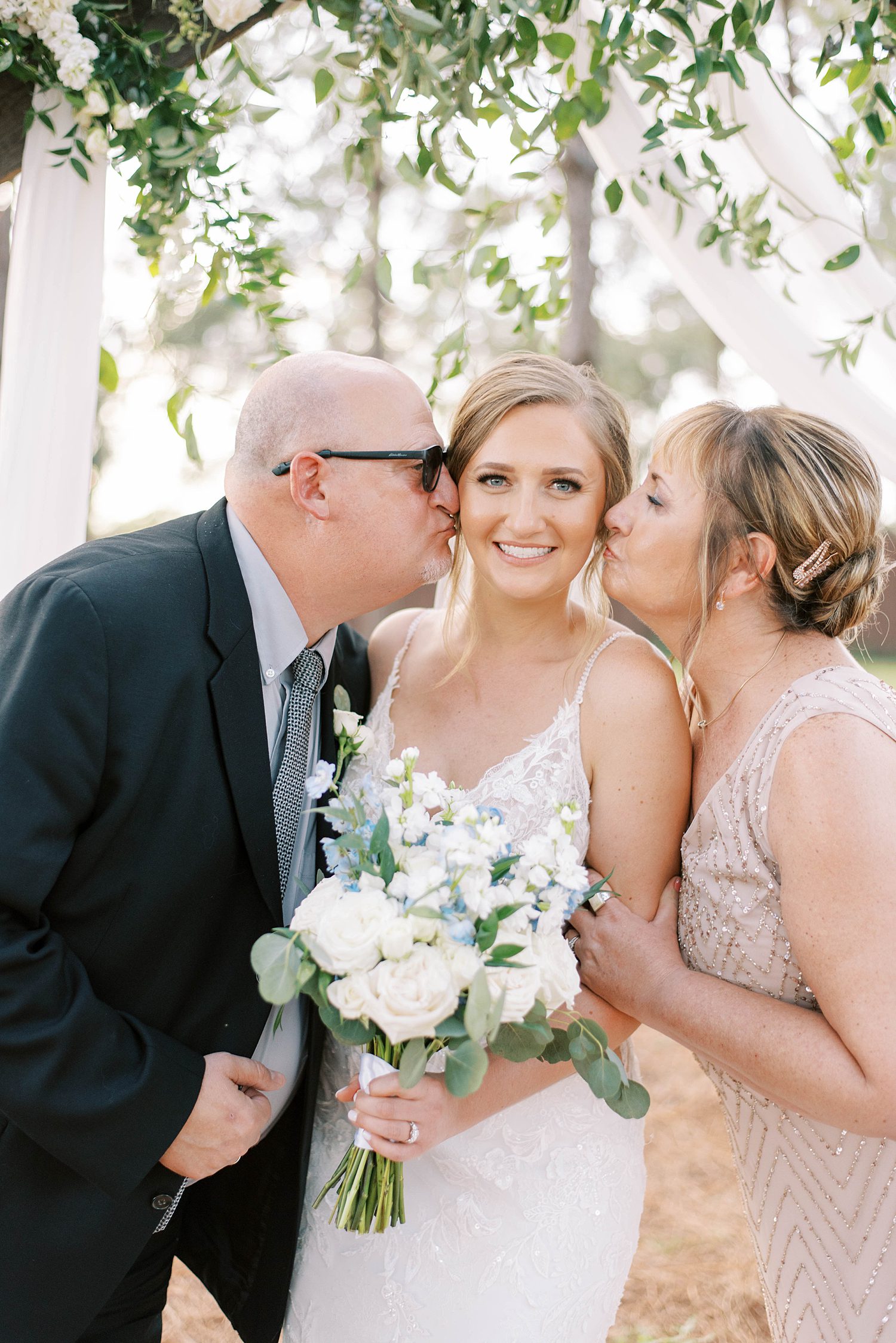 parents kiss bride on wedding day