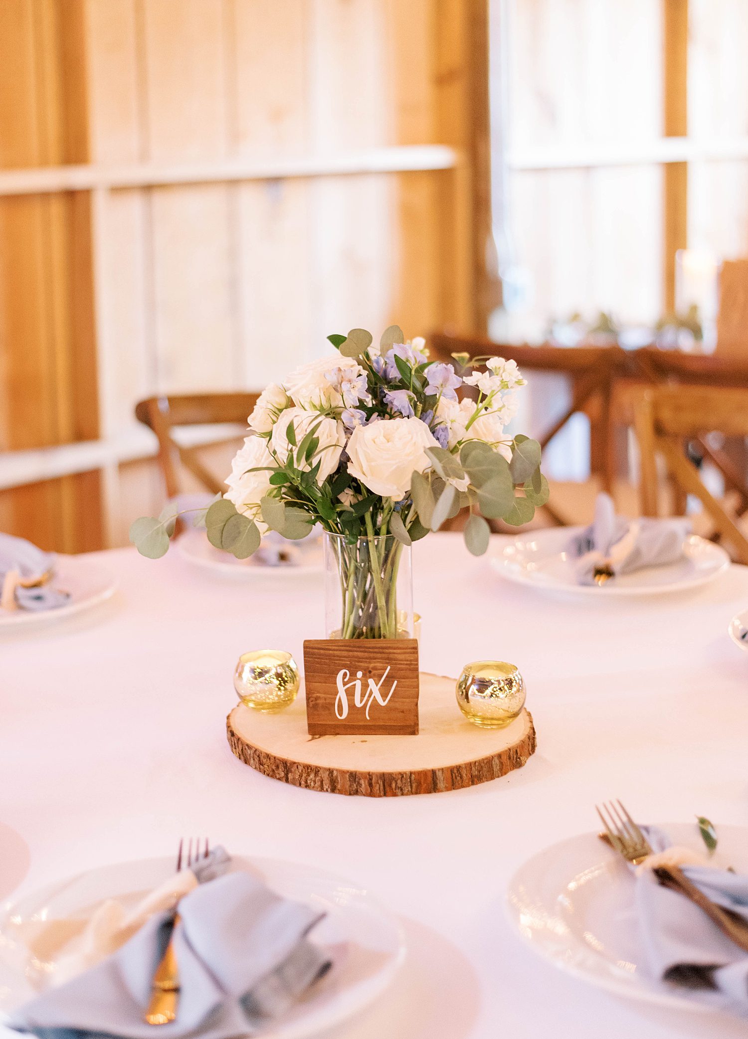 white and blue flowers sit on wooden charger at The Barn at Lone Oak Acres