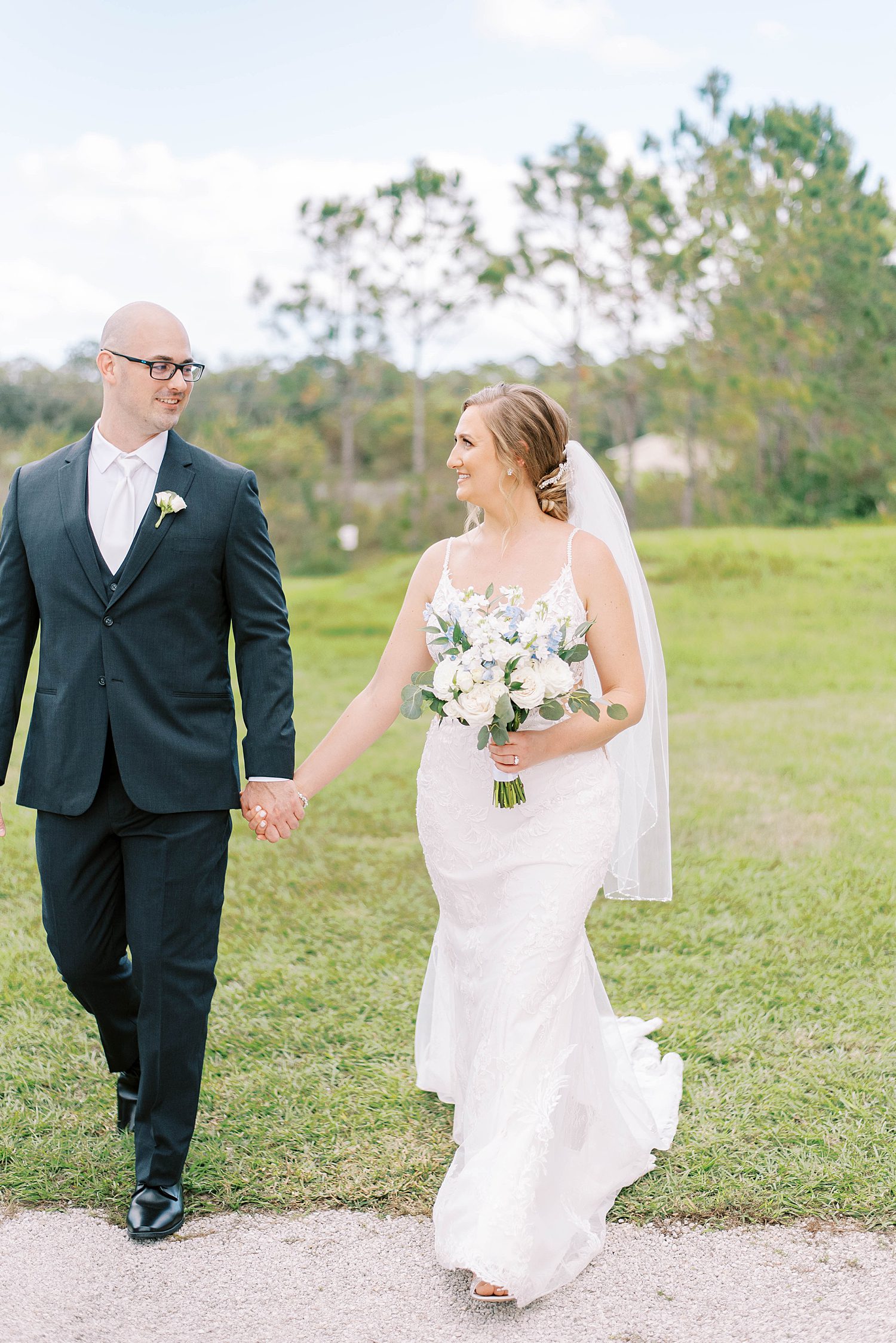 bride and groom hold hands walking through lawn at The Barn at Lone Oak Acres