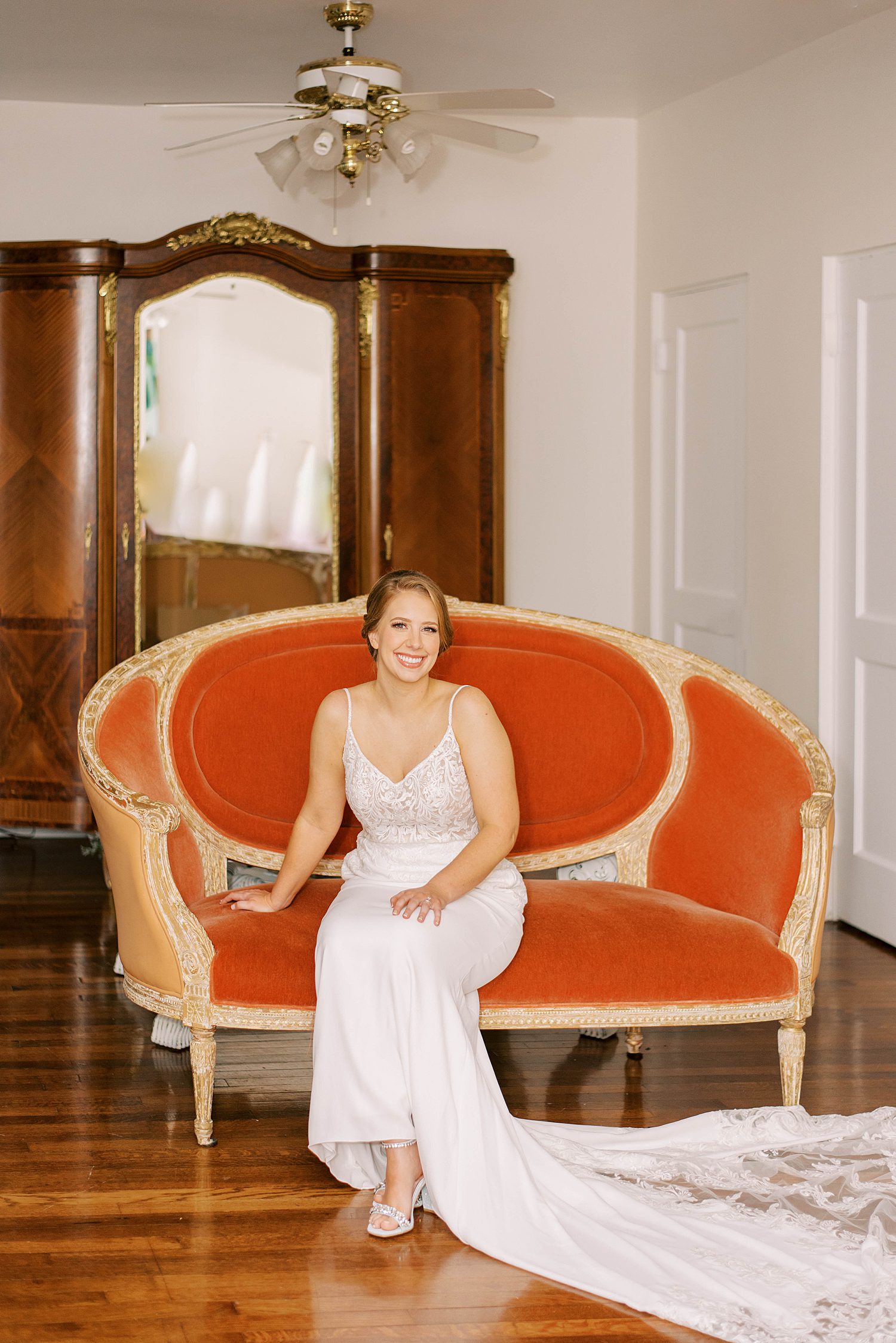 bride sits on orange and gold couch in bridal suite at Bella Cosa Lakeside