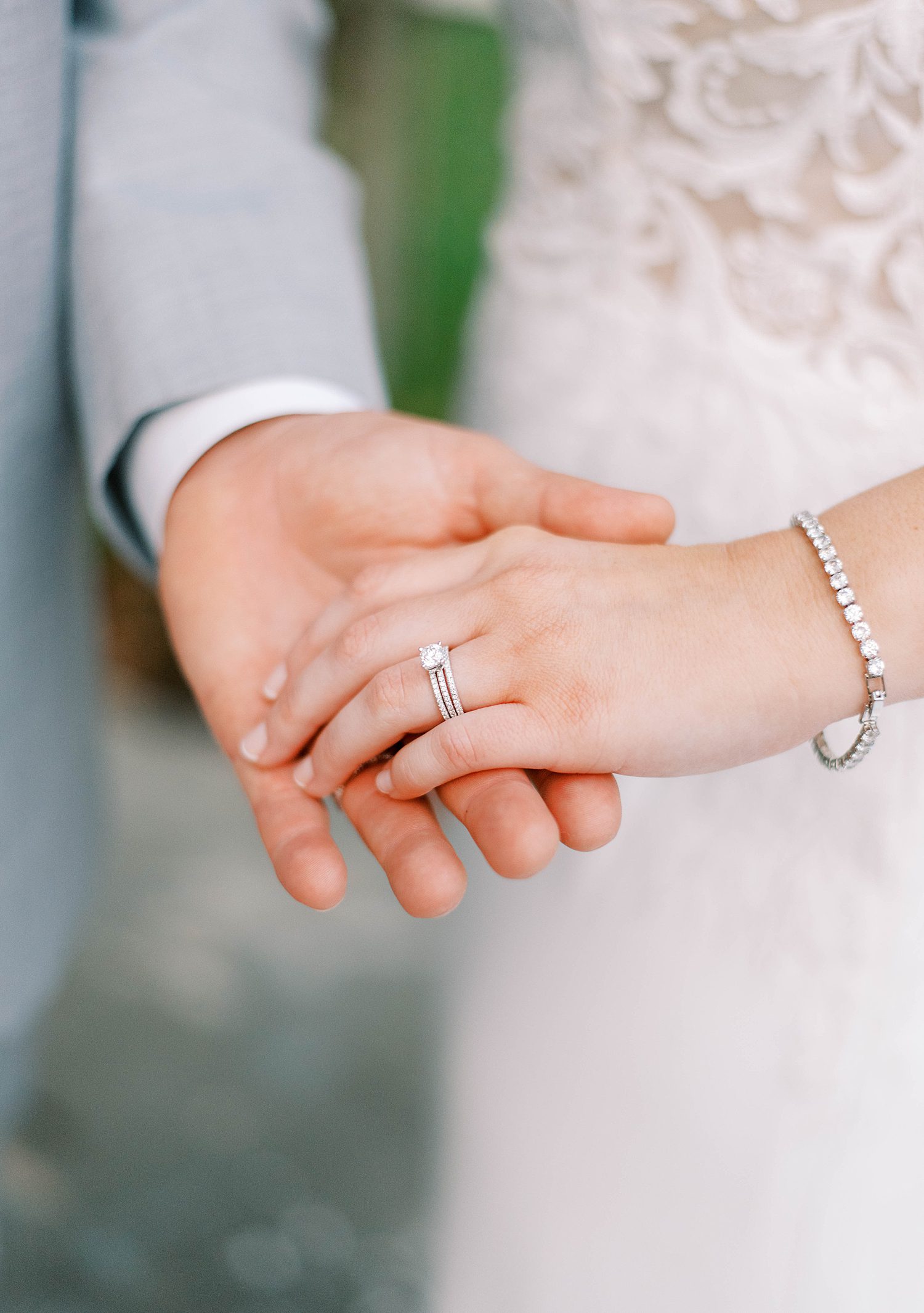groom holds bride's hand showing off engagement and wedding bands