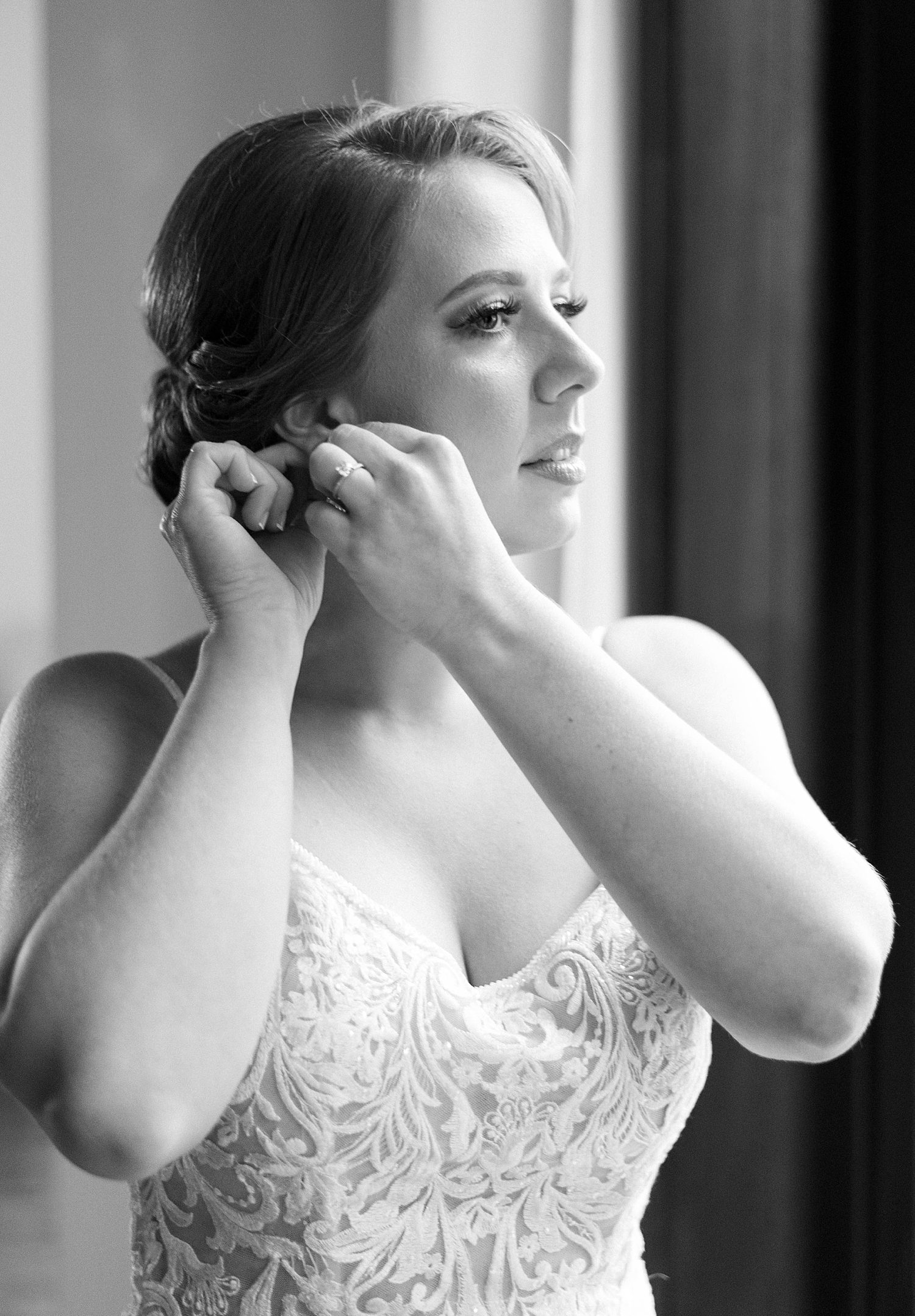 black and white portrait of bride adjusting earrings