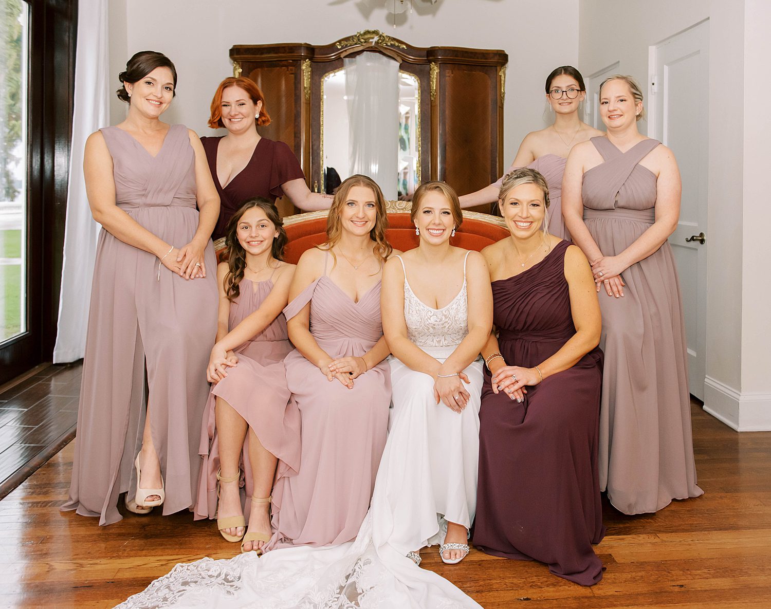 bride sits with bridesmaids in mauve gowns in suite at Bella Cosa Lakeside