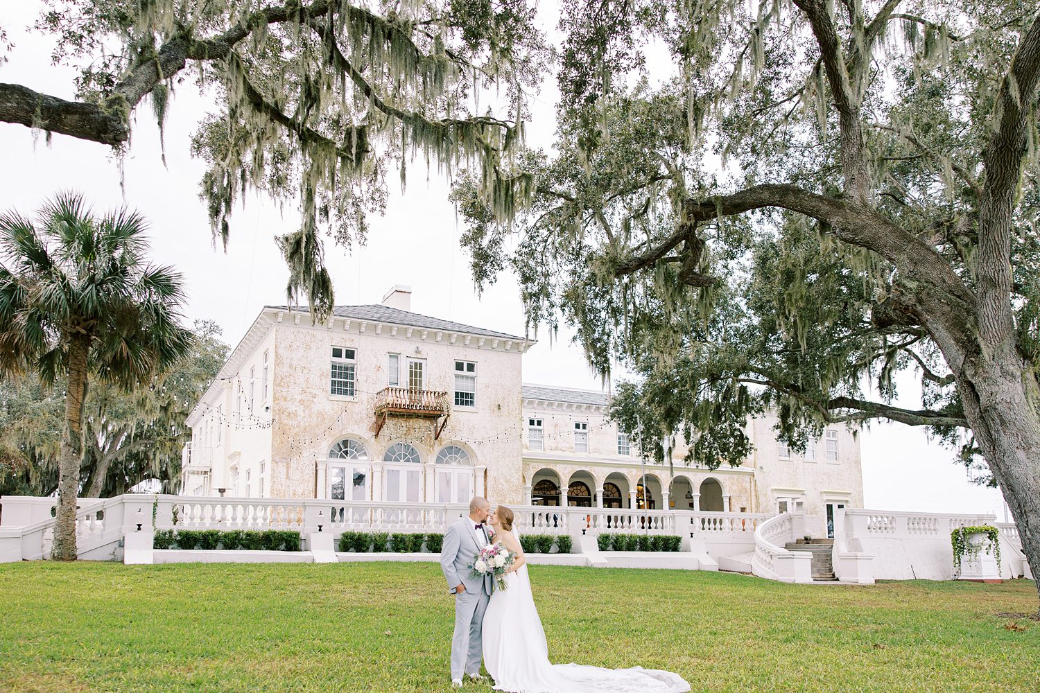 bride and groom kiss on lawn outside Bella Cosa Lakeside