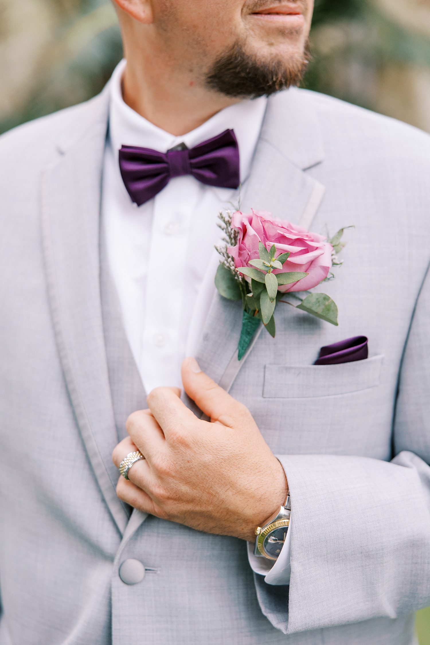 groom holds lapel of light grey suit