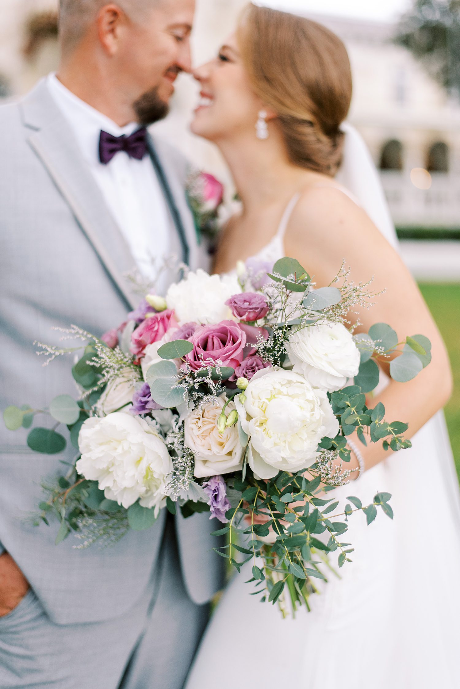 bride holds bouquet of ivory and purple roses