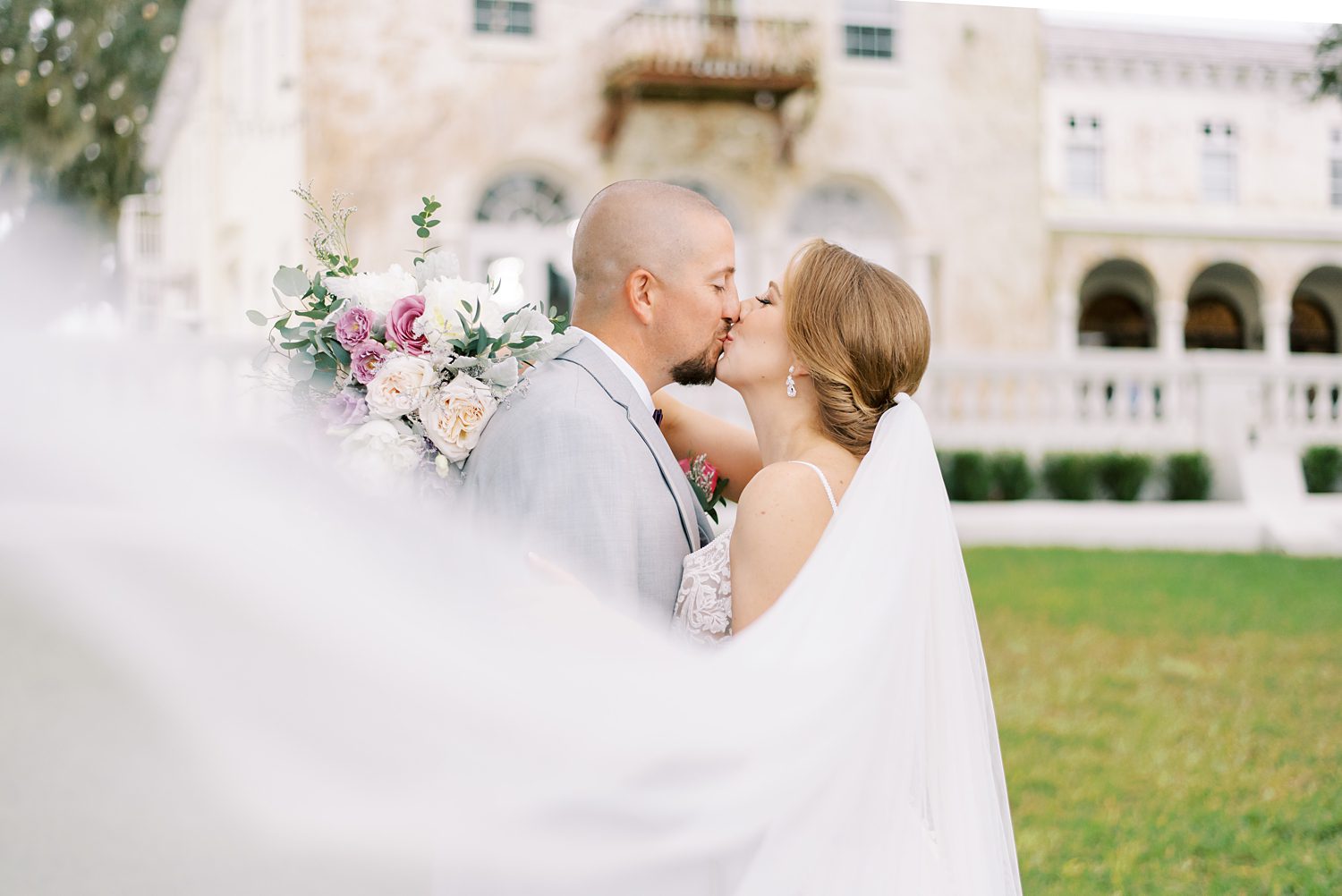 bride and groom kiss on lawn at Bella Cosa Lakeside