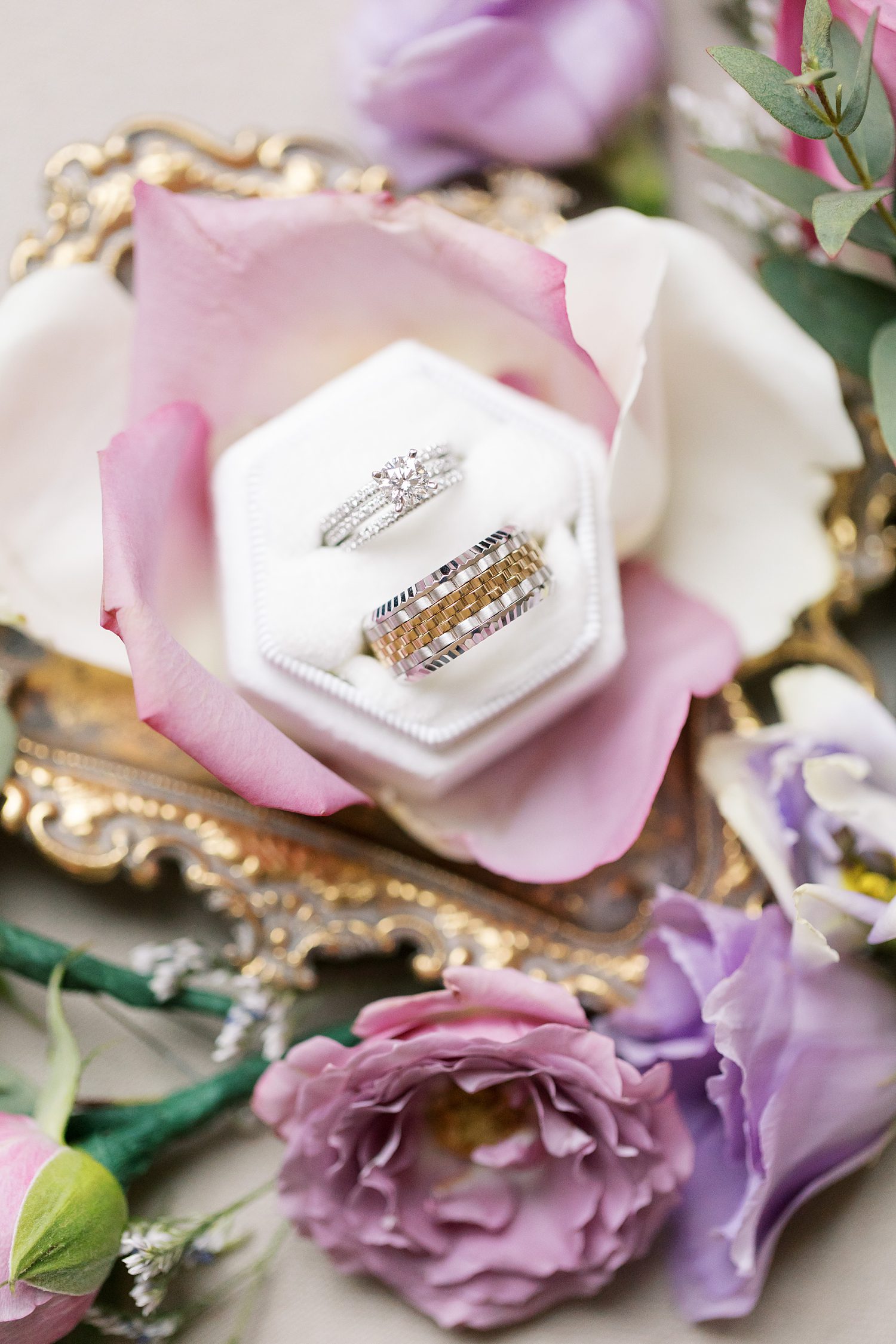 wedding rings rest in white ring box on pink petals