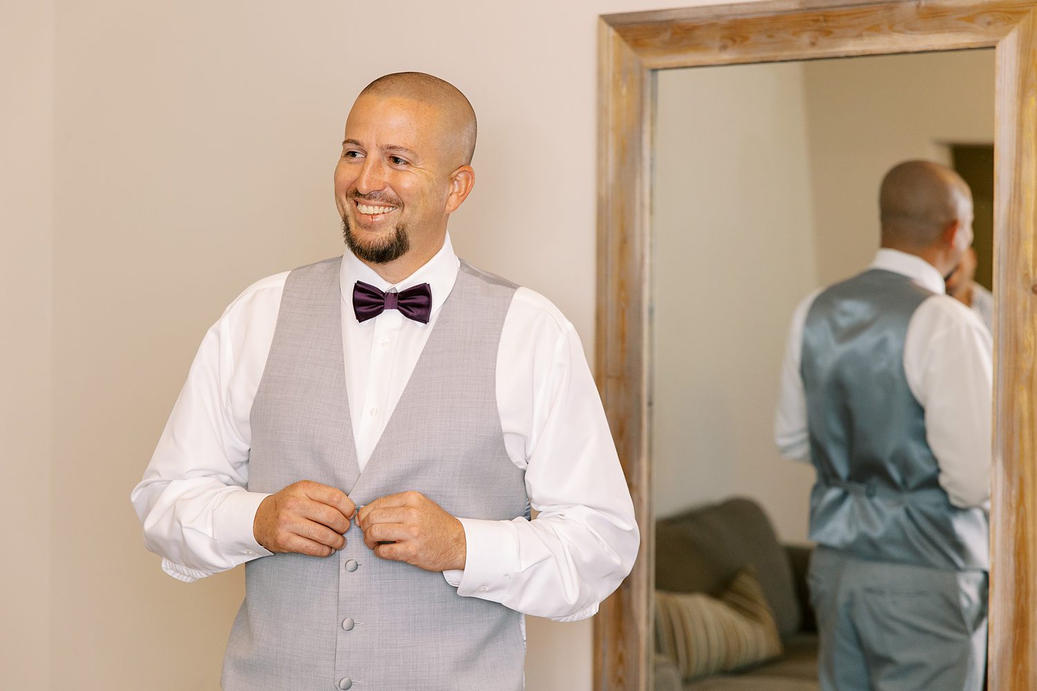 groom buttons up grey vest before Orlando wedding