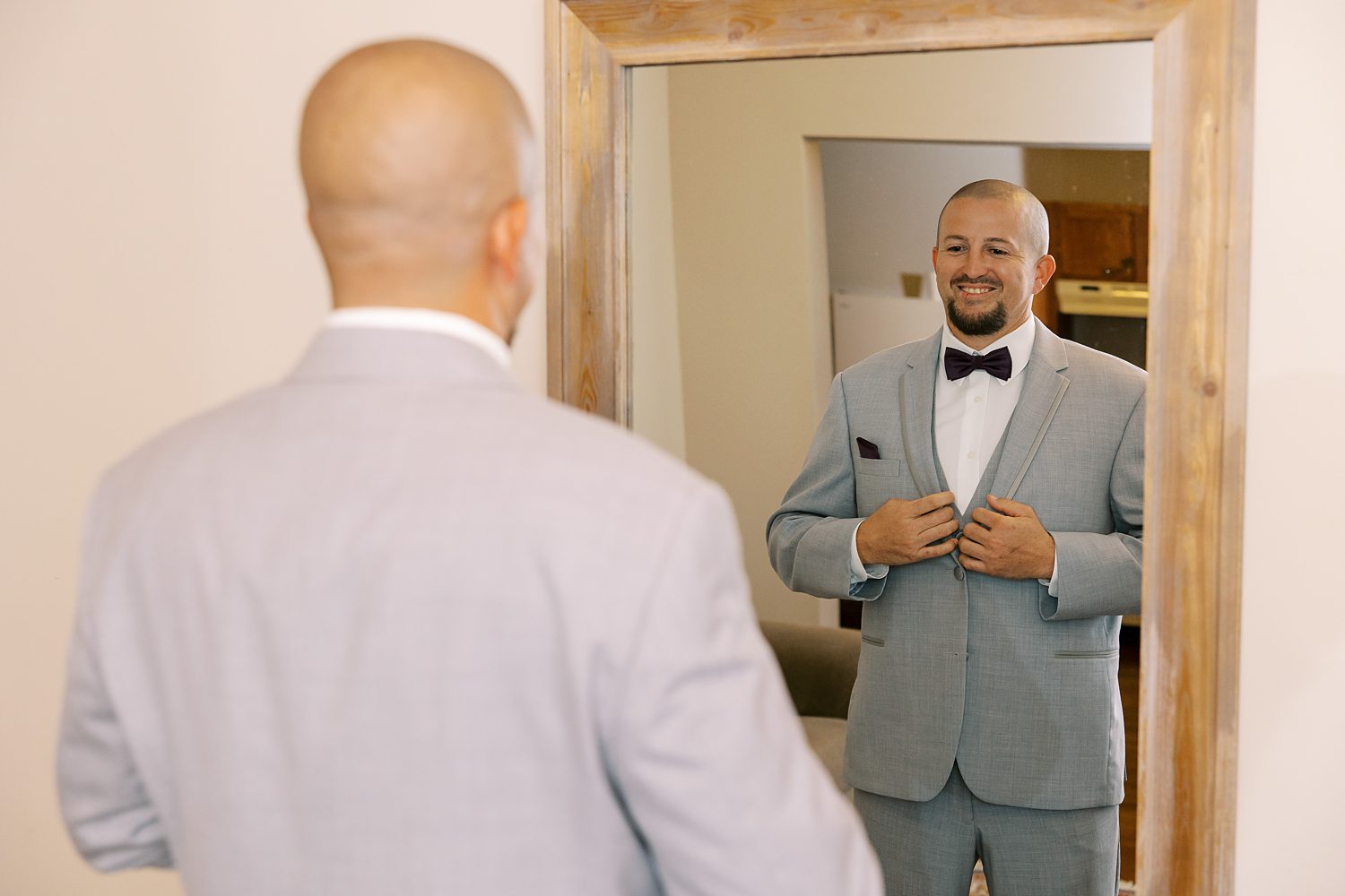 groom adjusts buttons on grey jacket before FL wedding