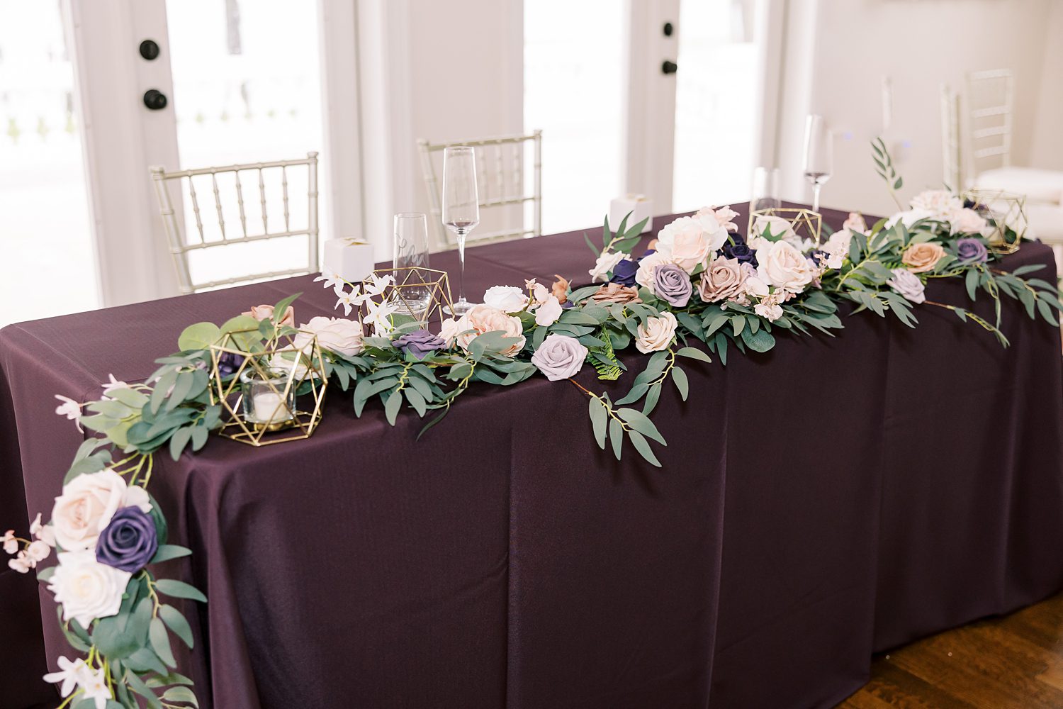 wedding reception with plum tablecloth and flowers draped across top