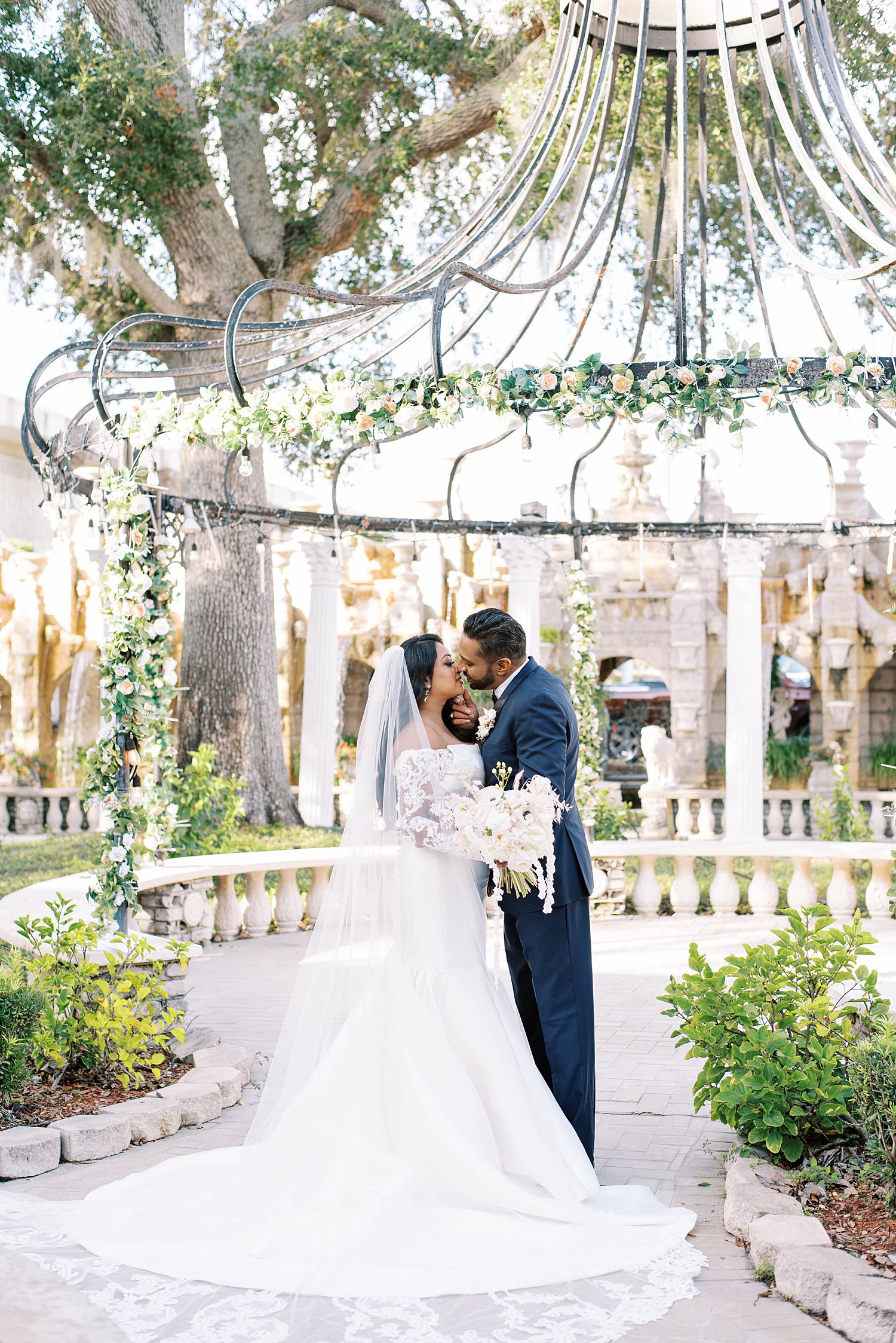 bride and groom kiss under greenery at Kapok Special Events