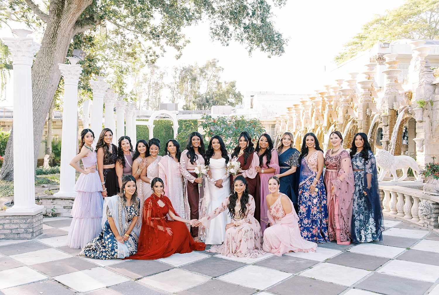 bride poses with bridesmaids in traditional Indian dresses in courtyard at Kapok Special Events