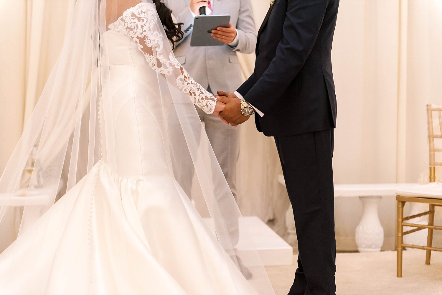 husband and wife hold hands during wedding ceremony at Kapok Special Events