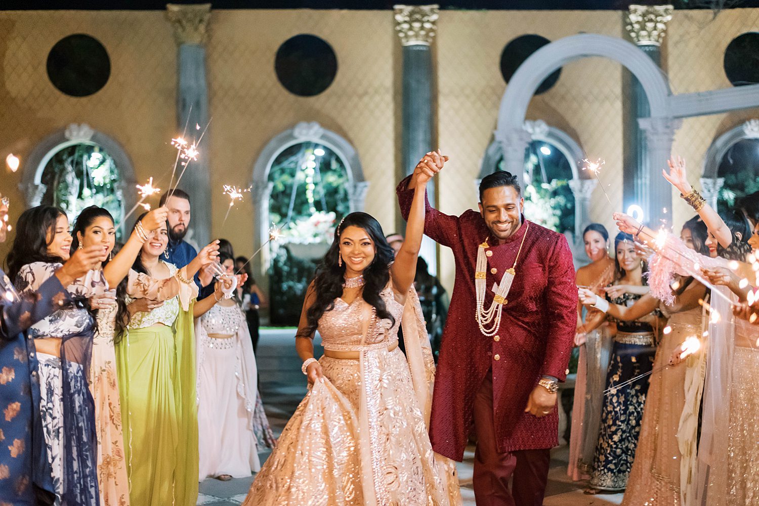 newlyweds leave wedding through sparkler exit in traditional Indian attire