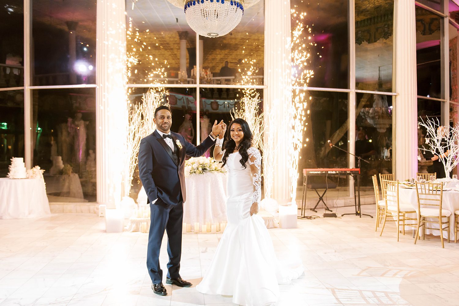 bride and groom pose by sweetheart table with sparklers
