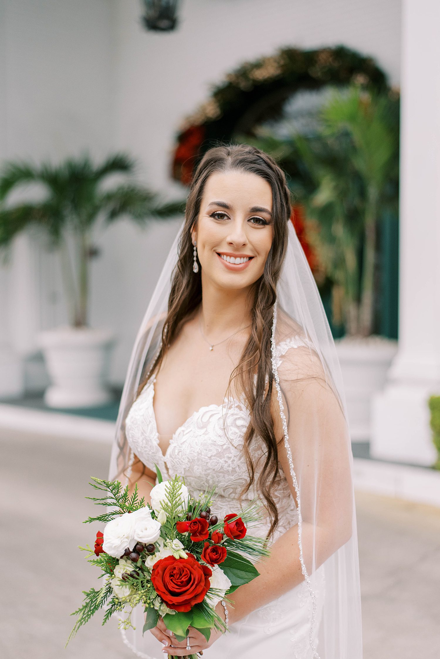 bride poses with red and white bouquet with veil around shoulders for Tampa FL wedding day 