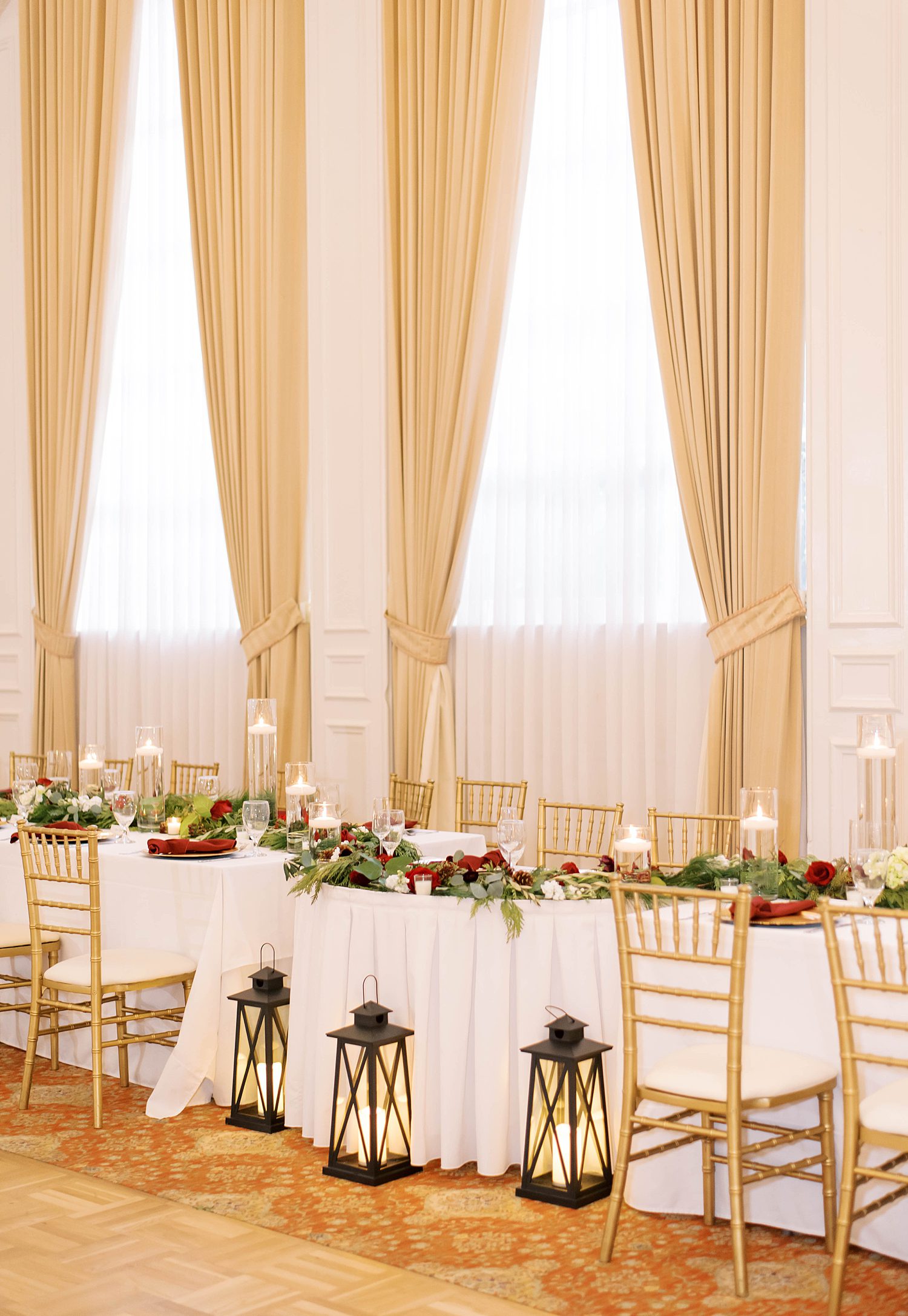 wedding reception with lanterns and head table with red flowers 