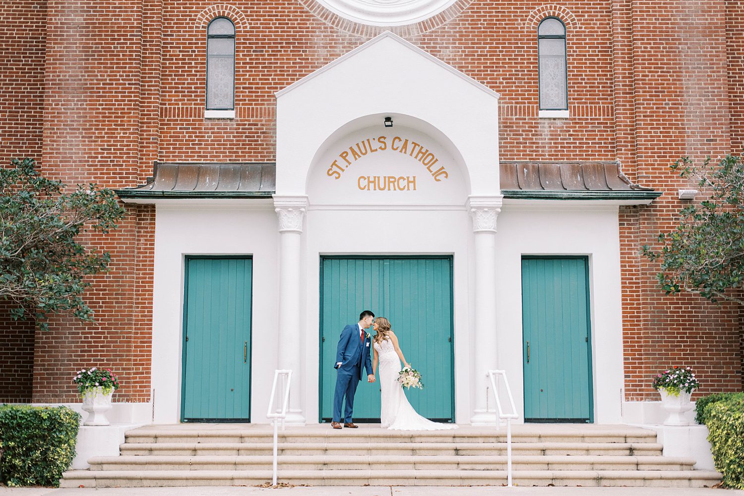 newlyweds hug by teal doors of St. Paul's Catholic Church in Tampa FL