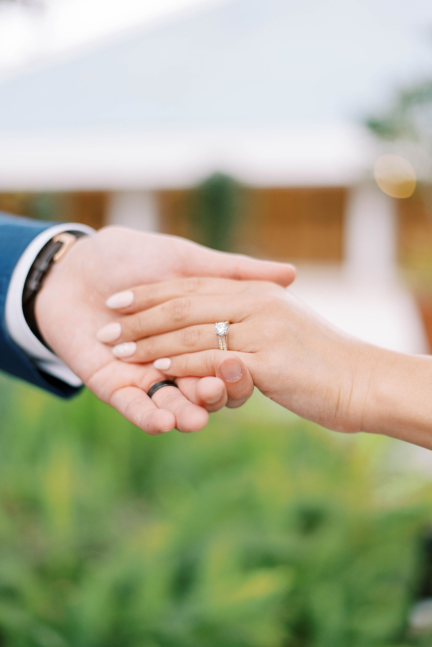 couple holds hands showing off bride's rings
