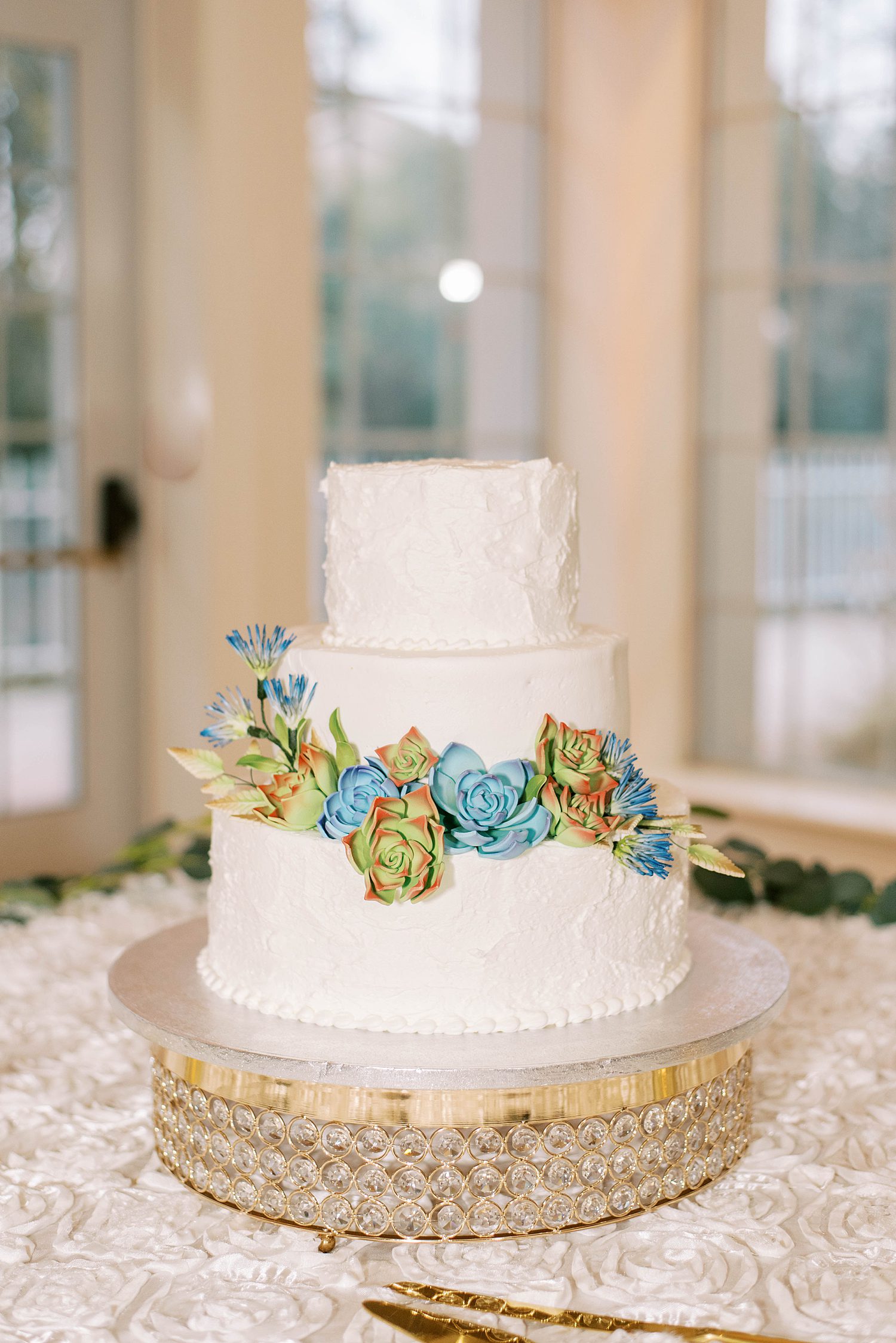 tiered wedding cake with blue and green succulents 