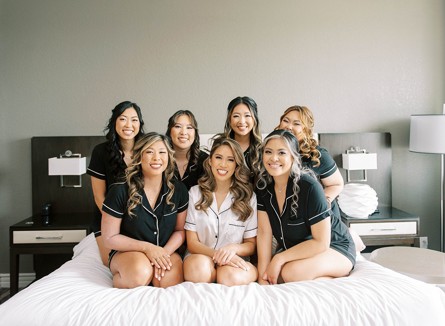 bride sits on bed with bridesmaids in matching pajamas 