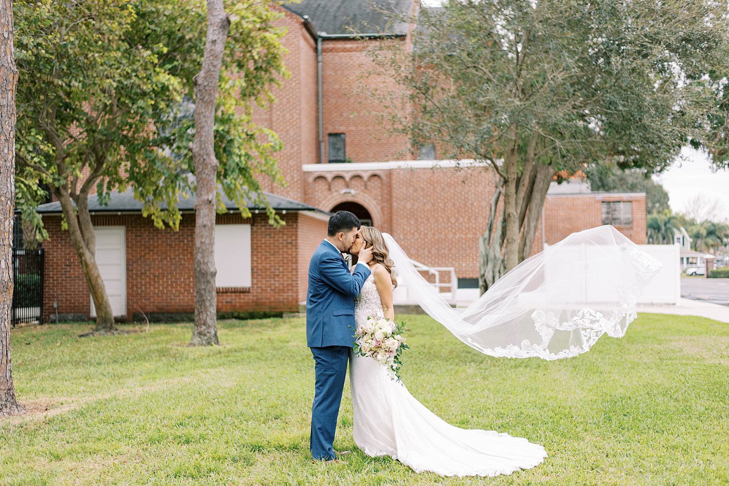 bride and groom kiss on lawn in Tampa FL