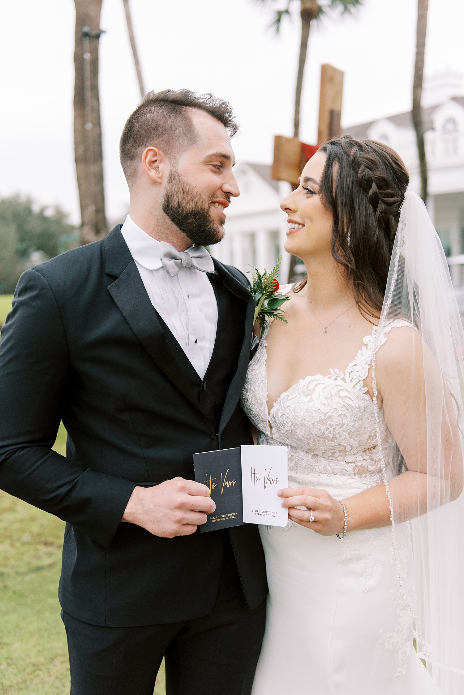 bride and groom smile together holding custom vow booklets 