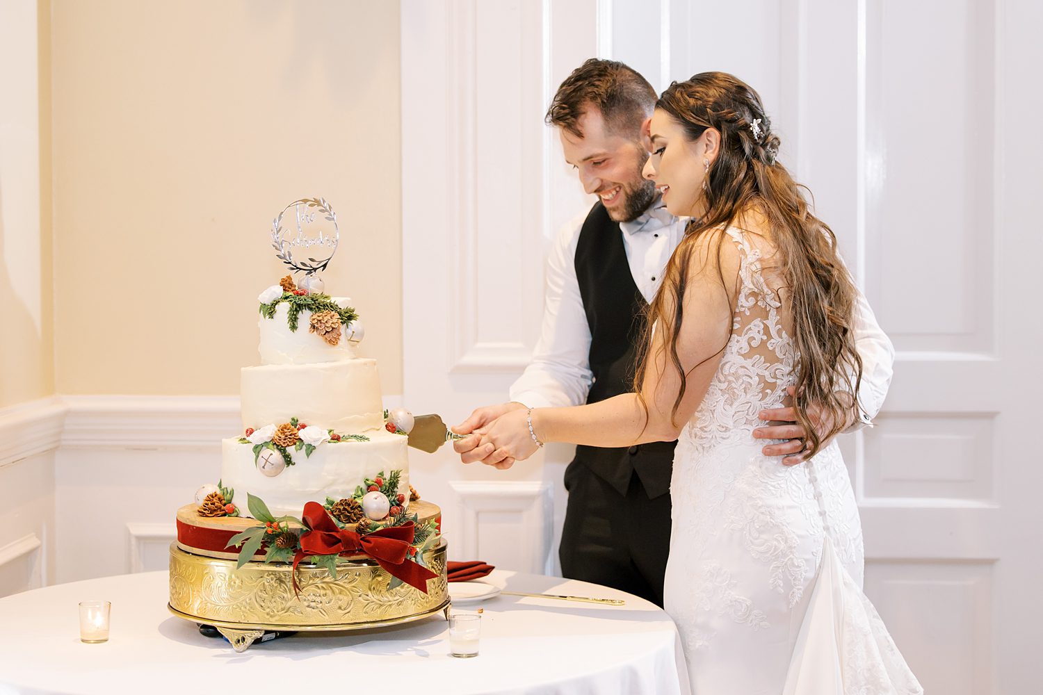 newlyweds cut wedding cake at Christmas inspired wedding reception