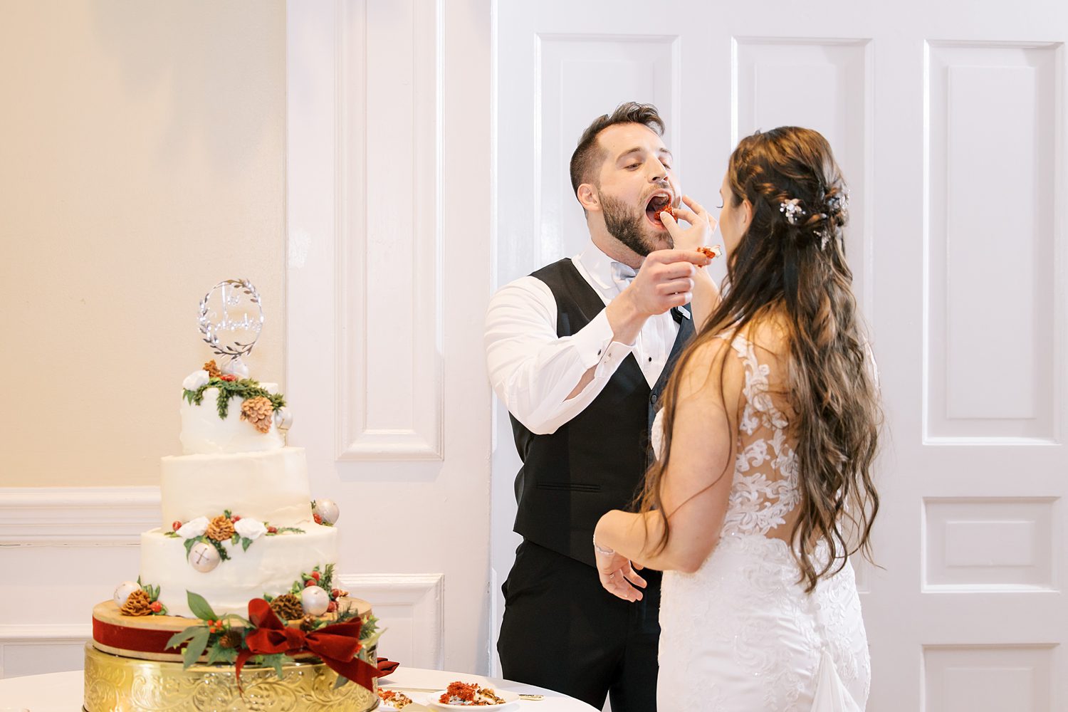 bride and groom feed each other cake during Christmas inspired wedding reception