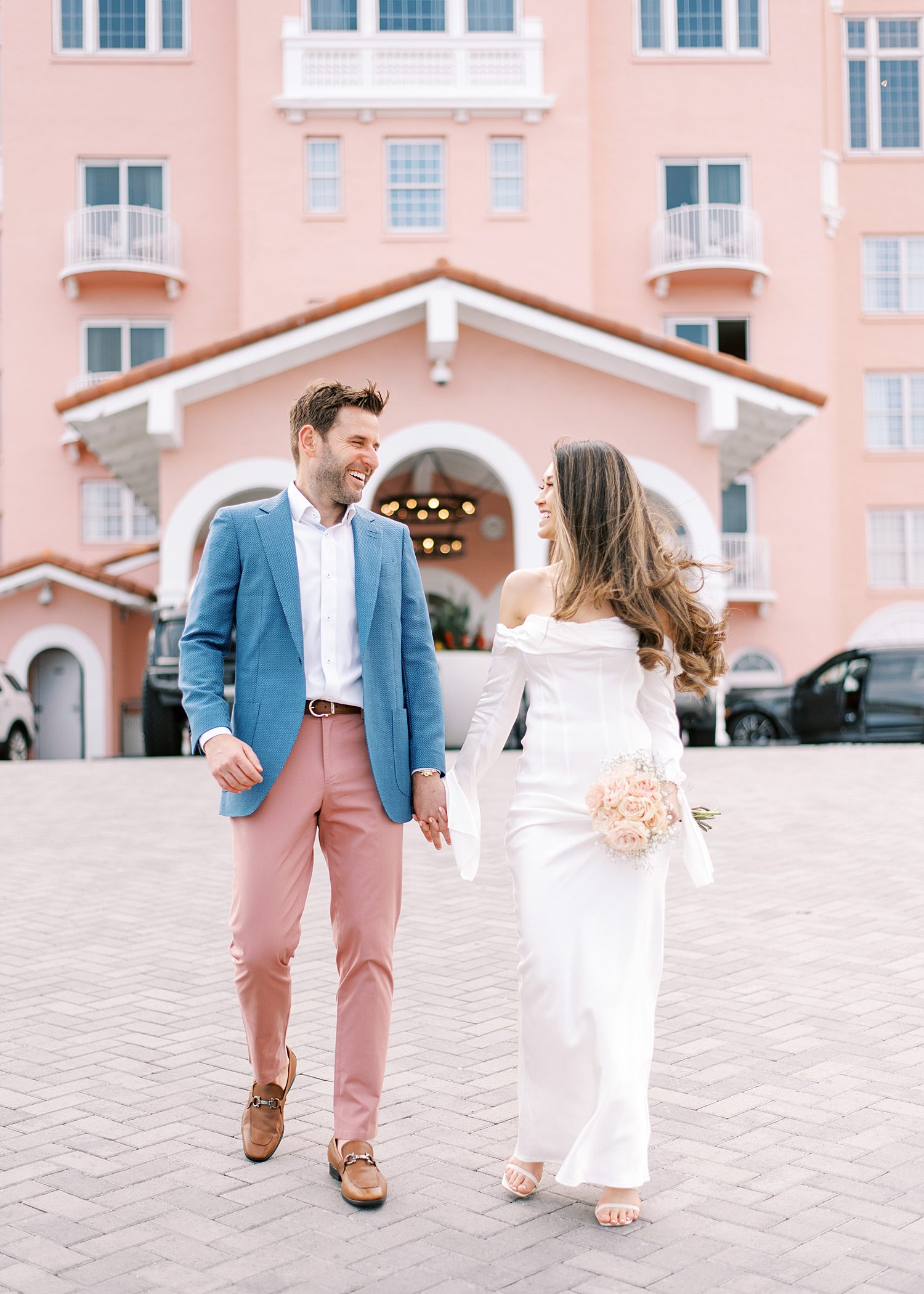engaged couple holds hands walking in front of the Don CeSar Hotel on St. Pete Beach