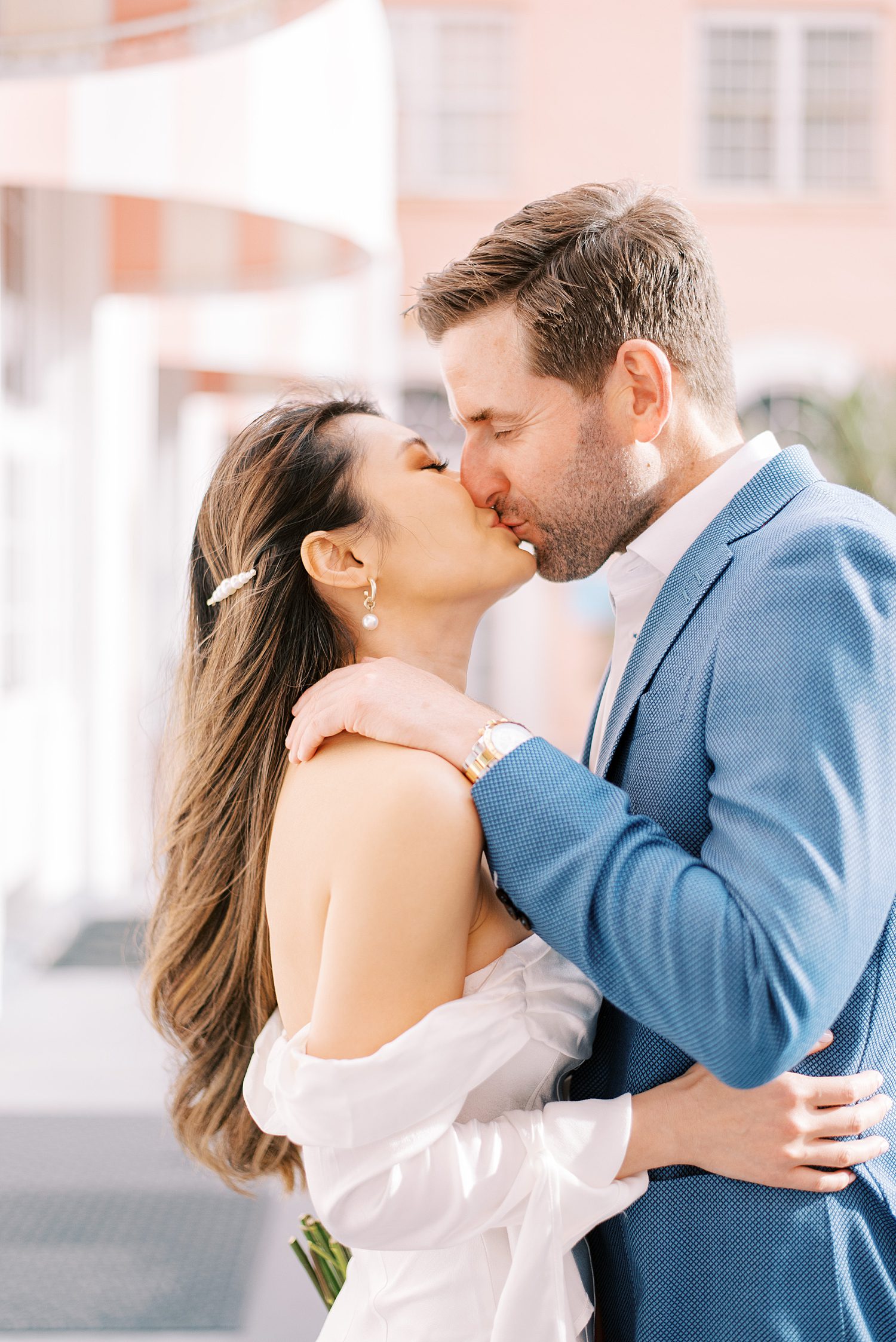 engaged couple kisses with pink hotel behind them during St. Pete Beach engagement session