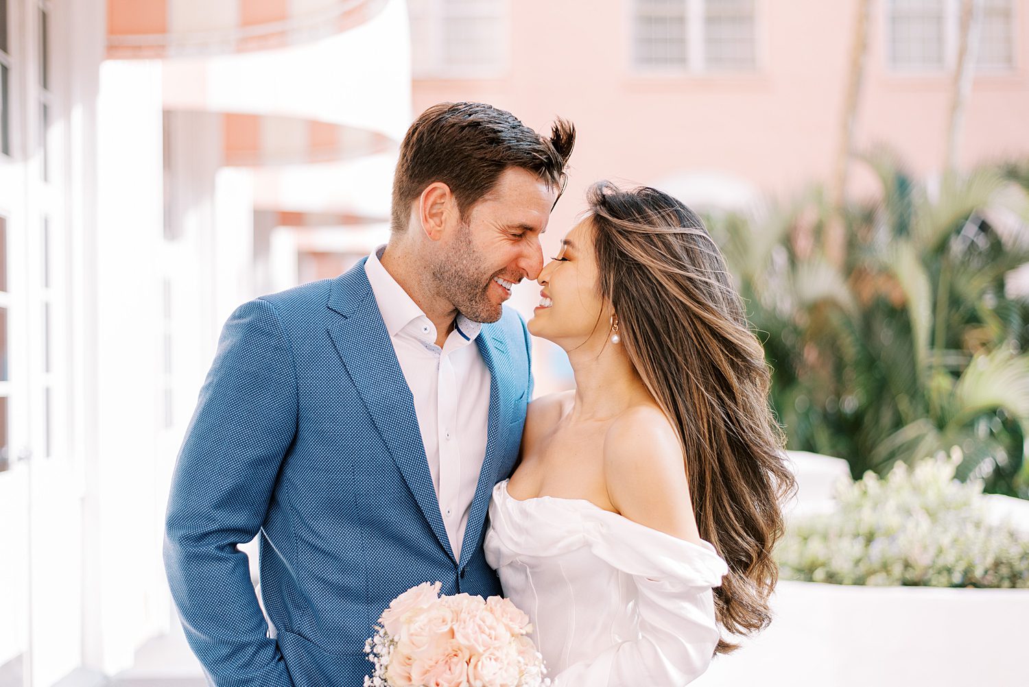 bride and groom lean together nuzzling noses outside the Don CeSar Hotel