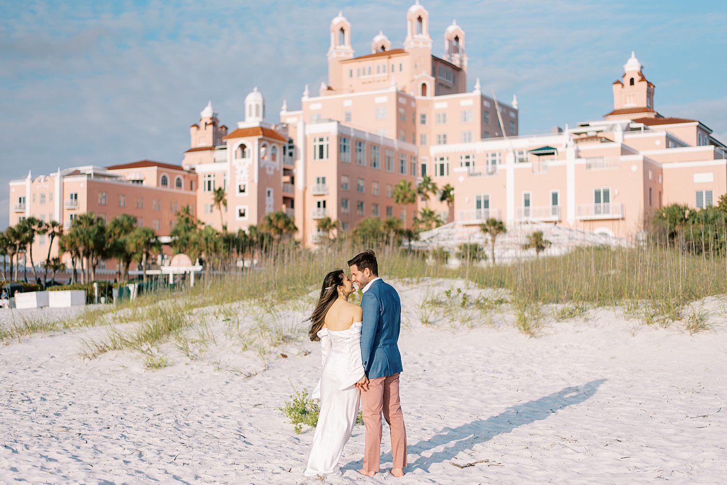 engaged couple kisses on sand in front of Don Cesar Hotel during St. Pete Beach engagement session