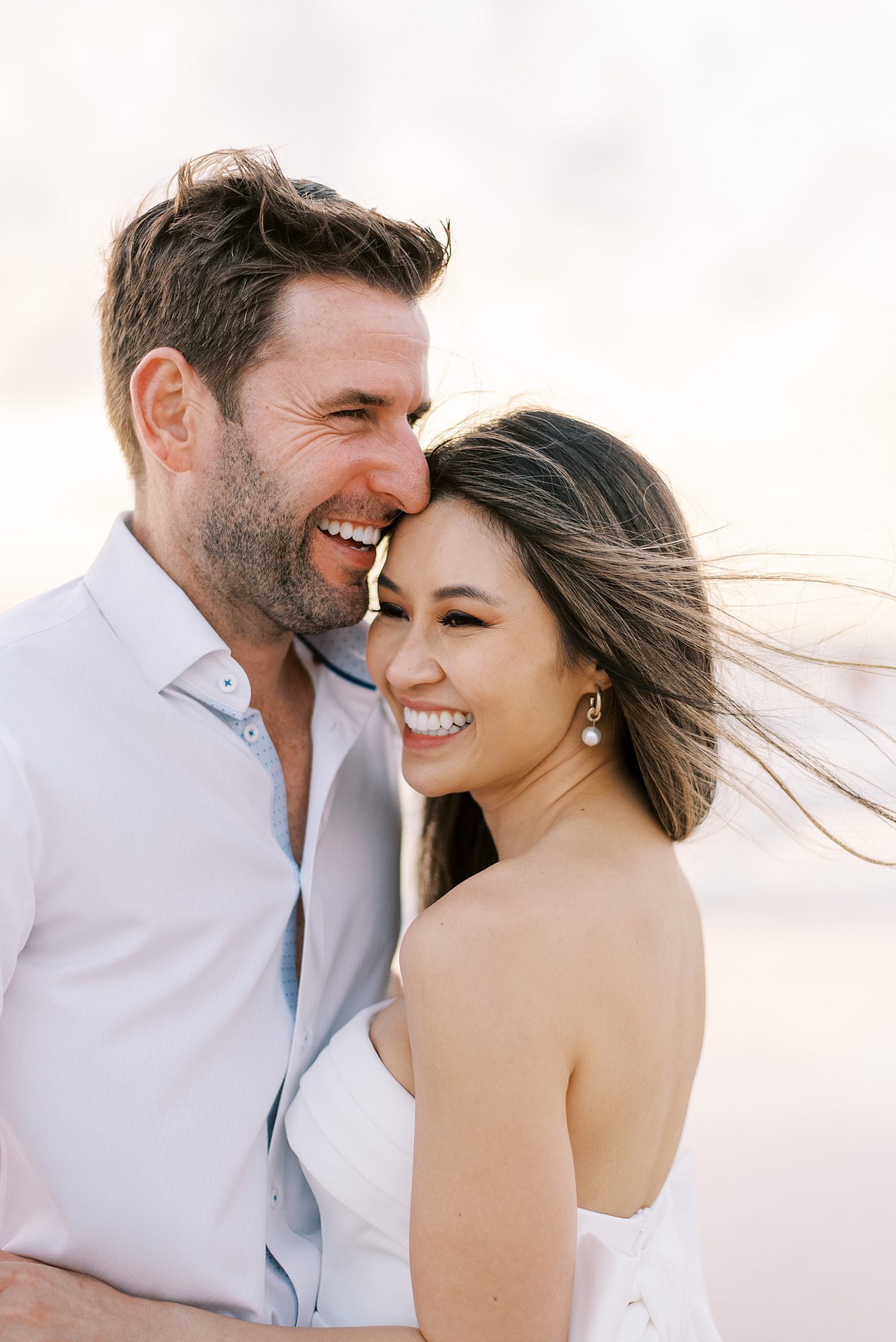 couple hugs laughing during engagement photos on the beach in Florida 