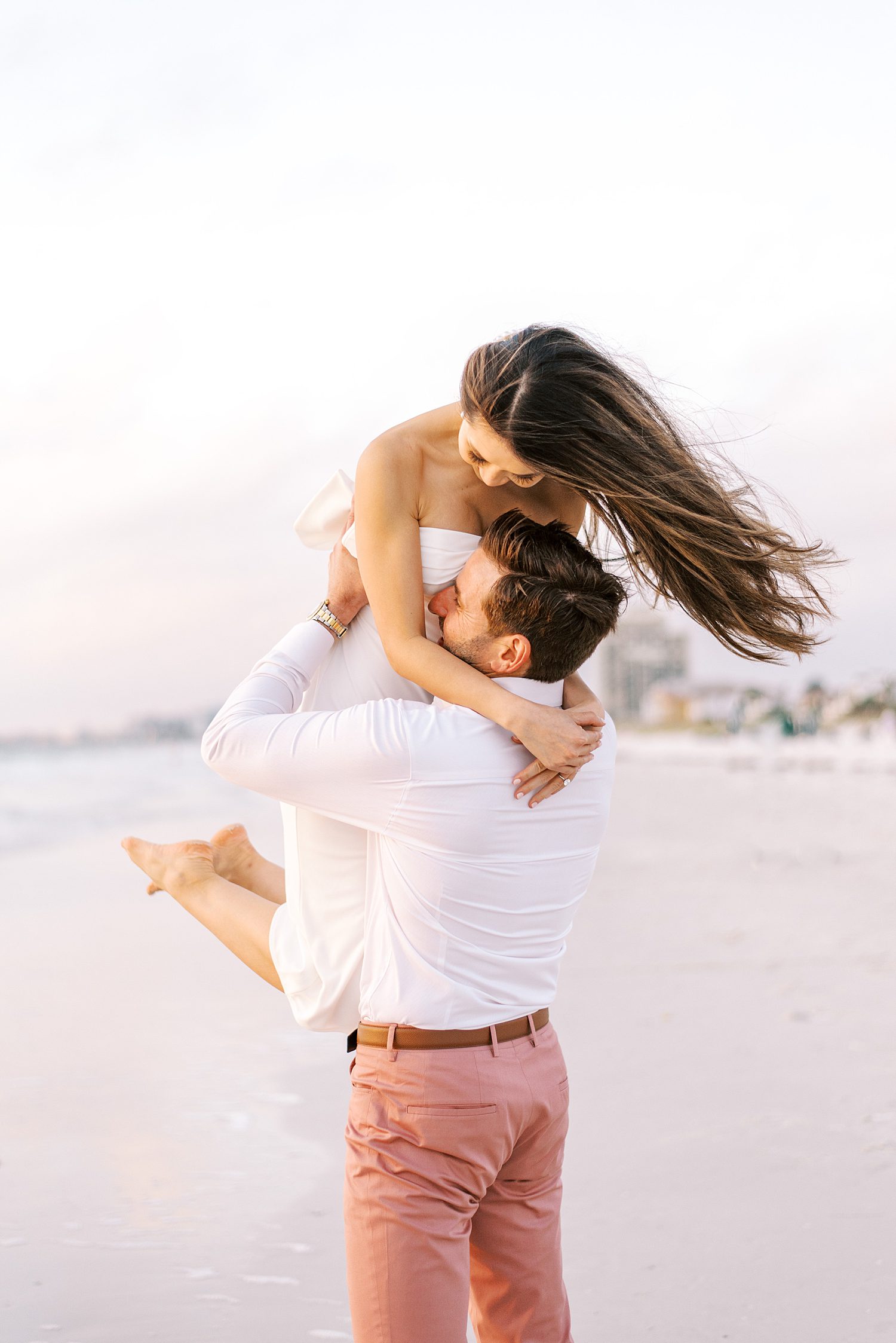 groom twirls bride around during St. Pete Beach engagement photos at sunset