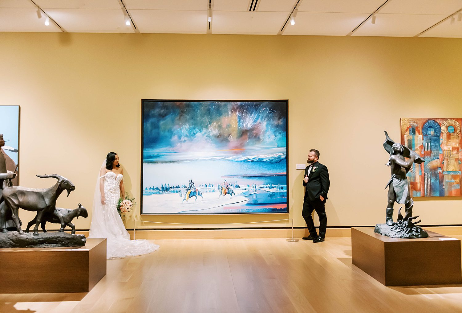 bride and groom stand next to painting in gallery of The James Museum