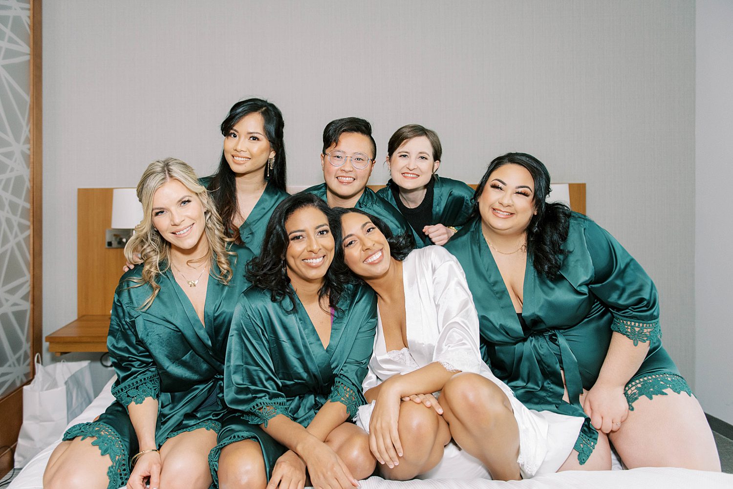 bride sits with bridesmaids in teal robes during prep for FL wedding