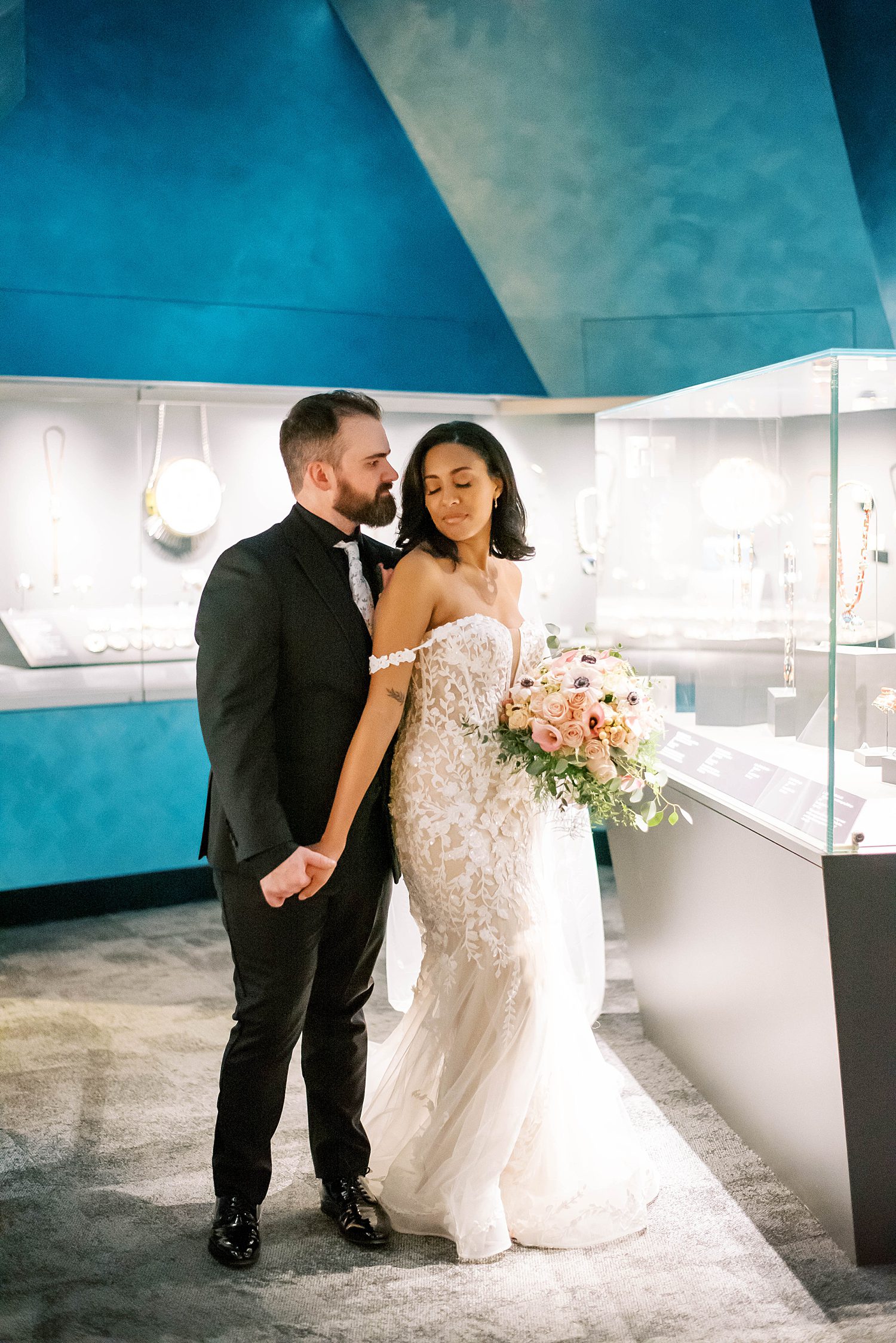 bride and groom pose in art gallery under blue headings