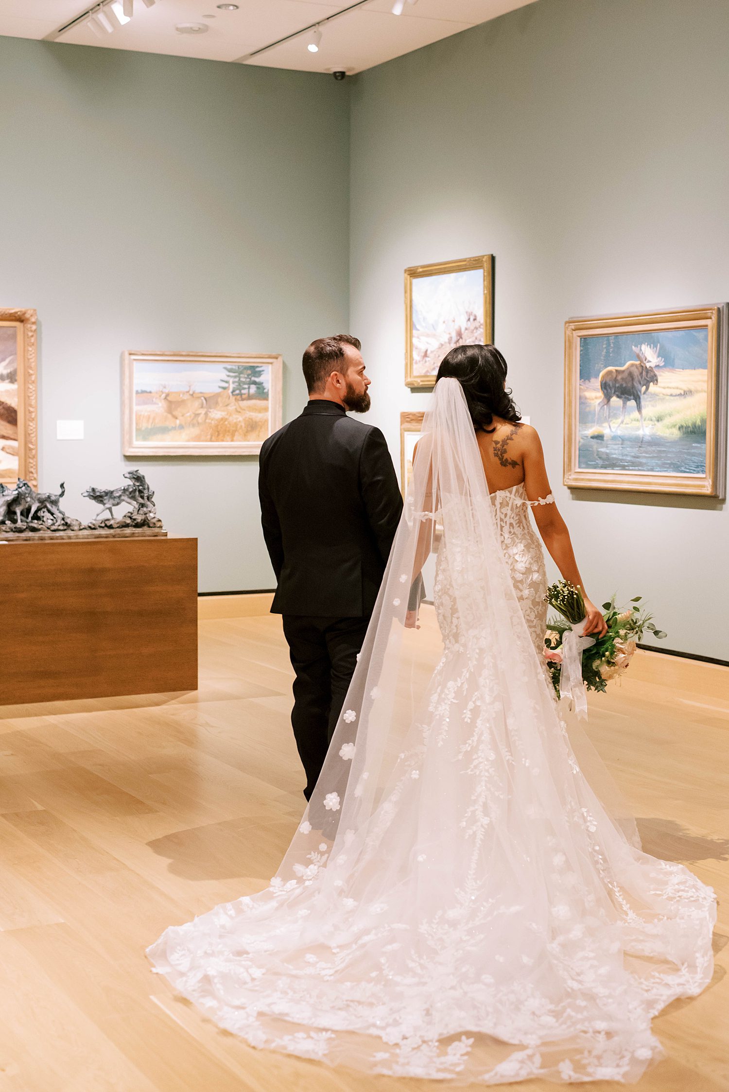 newlyweds hold hands walking through gallery at The James Museum