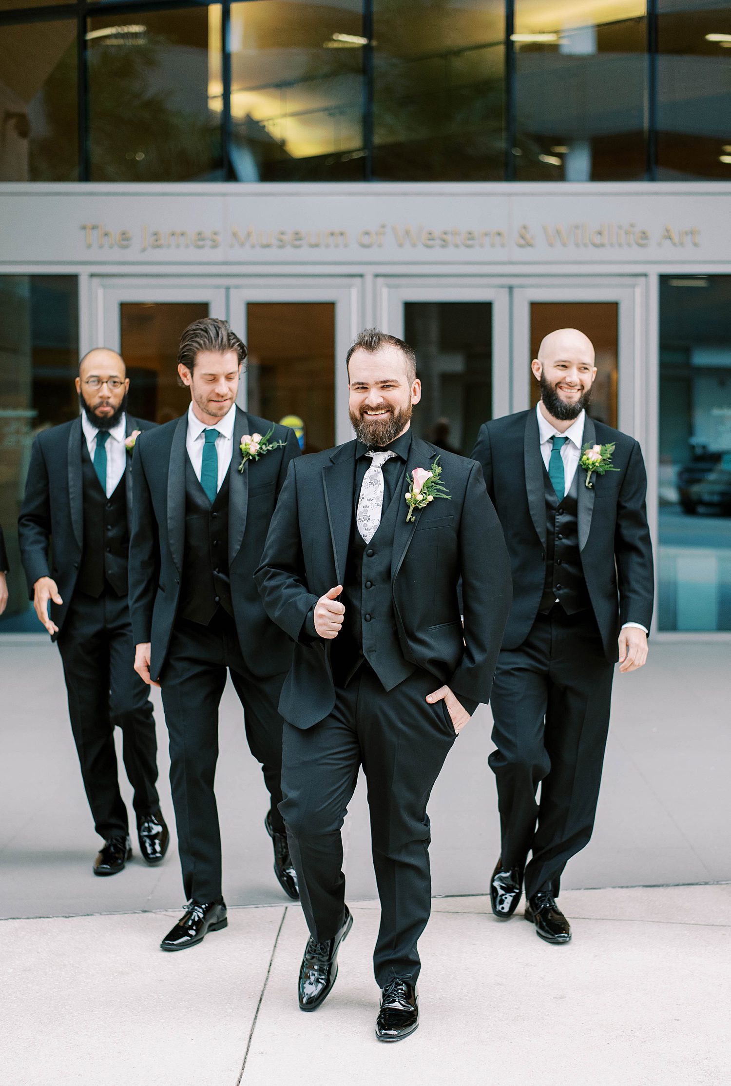 groom walks with groomsmen outside front of The James Museum