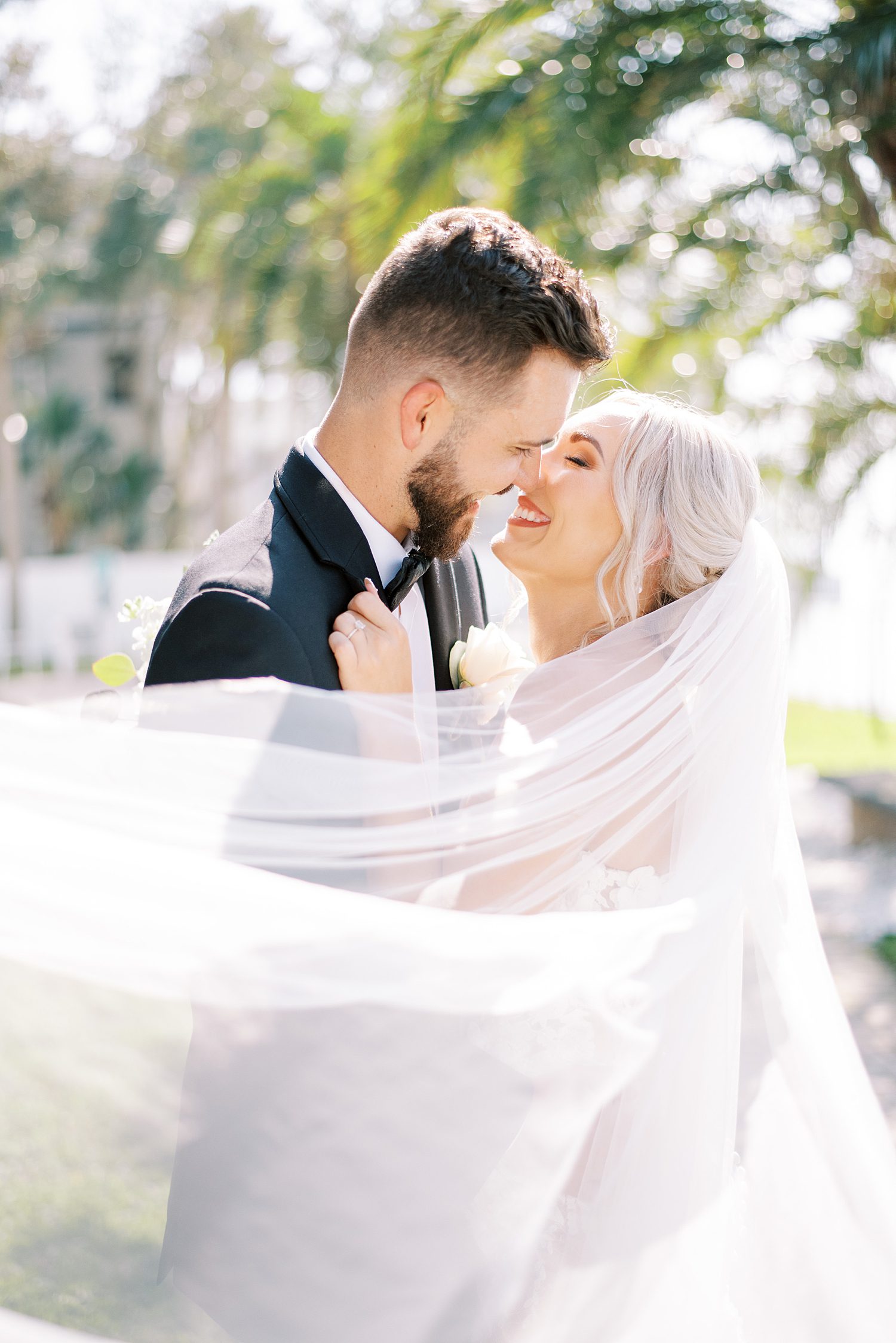 bride and groom laugh with veil around them